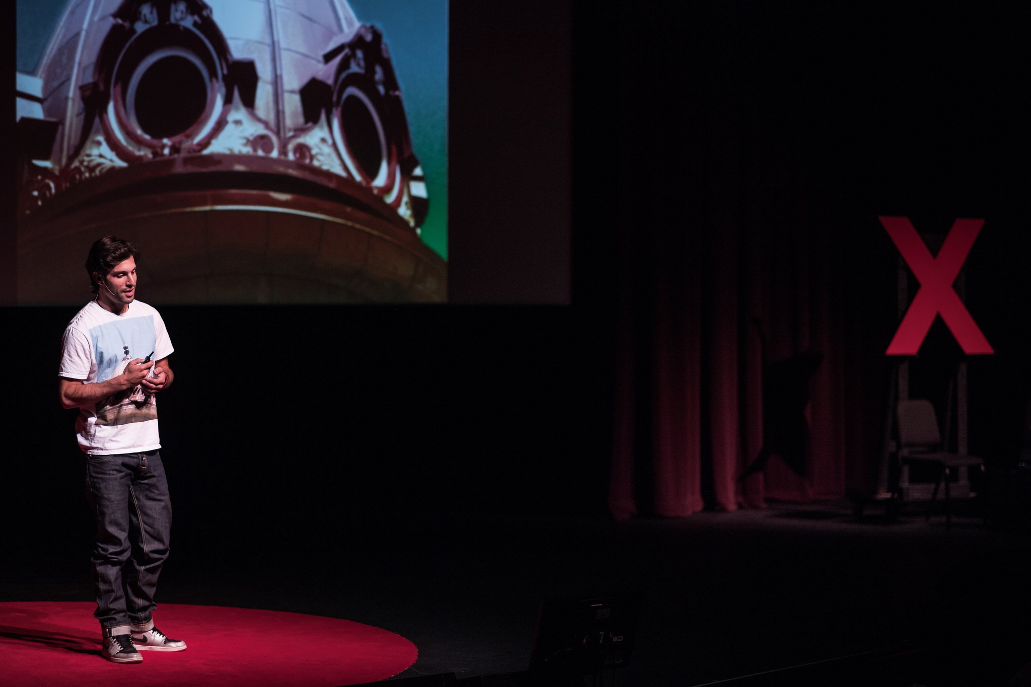 Alex Regen speaking on the TEDx stage about photography and the I SEE FACES project