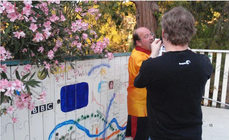 Robert Scoble interviewing Marc Canter in front of his "Open Mesh" fence mural.