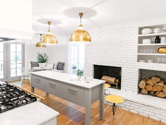 I can just envision what a lovely place this would be to prepare dinner, lots of natural light shining in through the gorgeous french doors, I would most likely would be sipping a glass of wine..some country music blaring..I'd be dancing along...the fire going...yes...this is heavenly! And, I just love the antique brass pendant lighting hanging over the island..and I also love the pretty kitchen nook in the corner it is a great place for the kids to do their homework and hang with Mommy :)