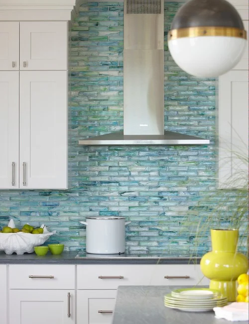 The shimmer of an iridescent tile backsplash calls to mind the glint of sun on crystal-clear water and pearly shells beneath the waves.