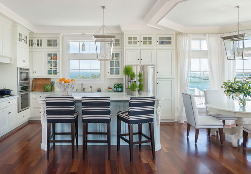Bring a touch of color to a white kitchen with a touch of nautical style elements. This kitchen is gorgeous, I love the designer choice to let the view be the star of this room. The nautical blue and white kitchen stools, flowers and greenery is all the color this kitchen needs.
