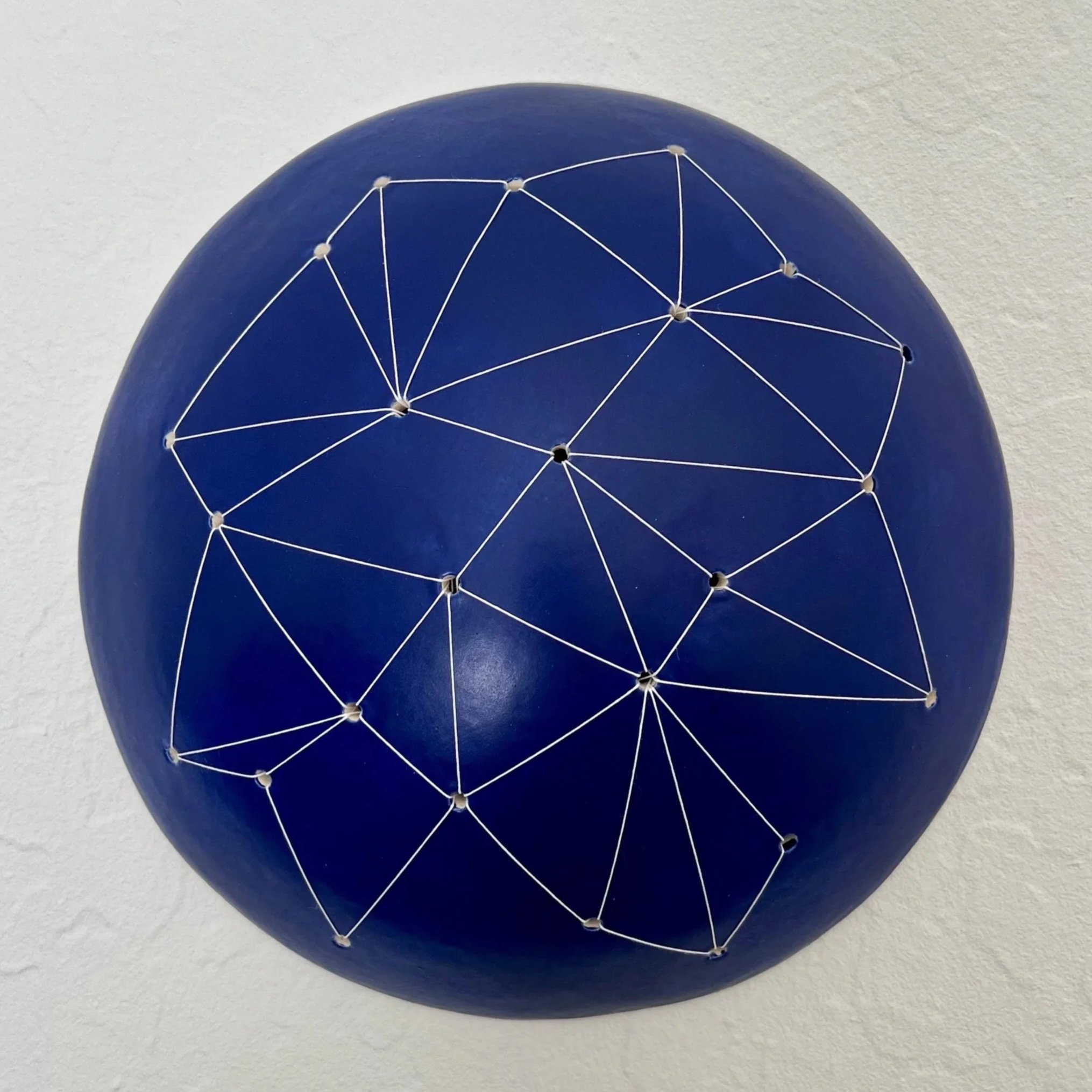 dark blue ceramic dome sewn with white thread resembling a constellation