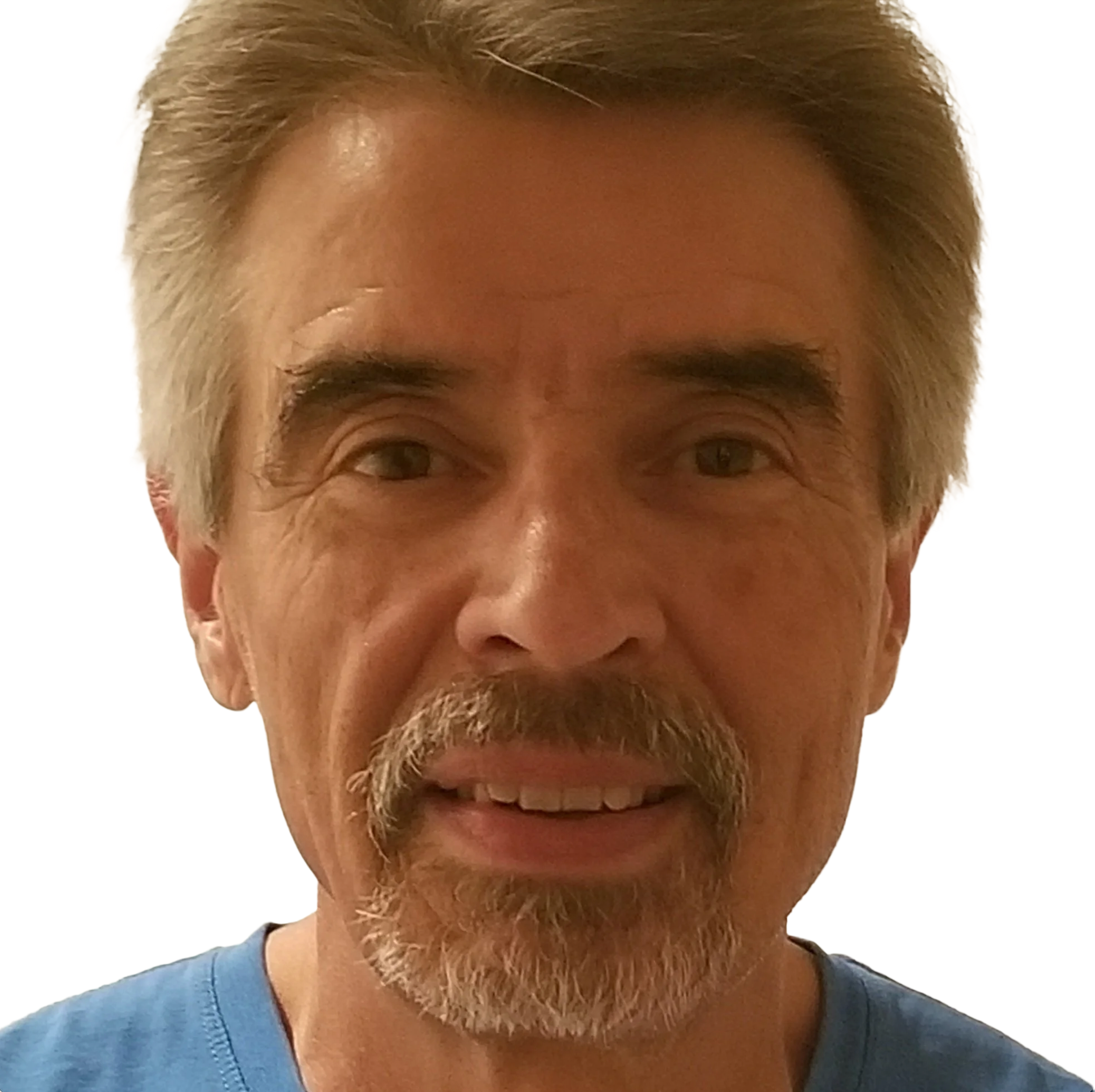 Close-up of an older man with gray hair and beard, smiling, wearing a blue shirt.