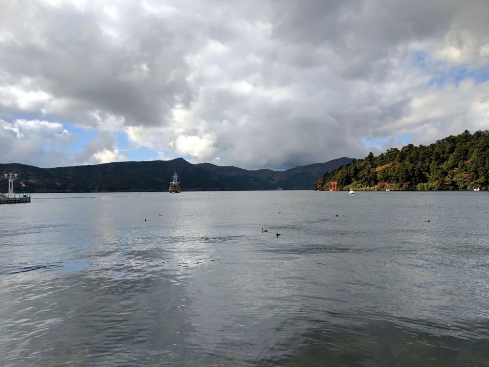 Looking out over Lake Ashinoko with the Hakone Shrine torii gate and Mt. Fuji hidden behind clouds