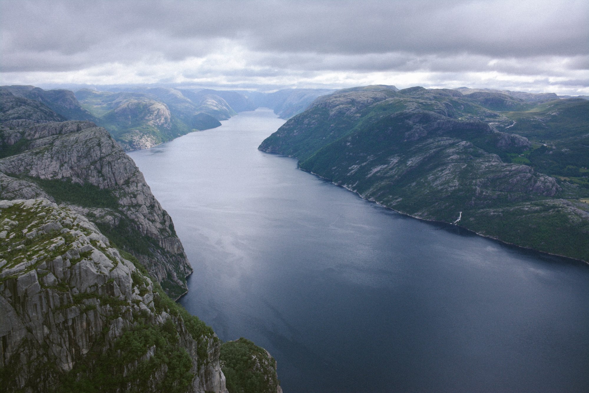 Vue aérienne d'un fjord en Norvège, sous un ciel nuageux.