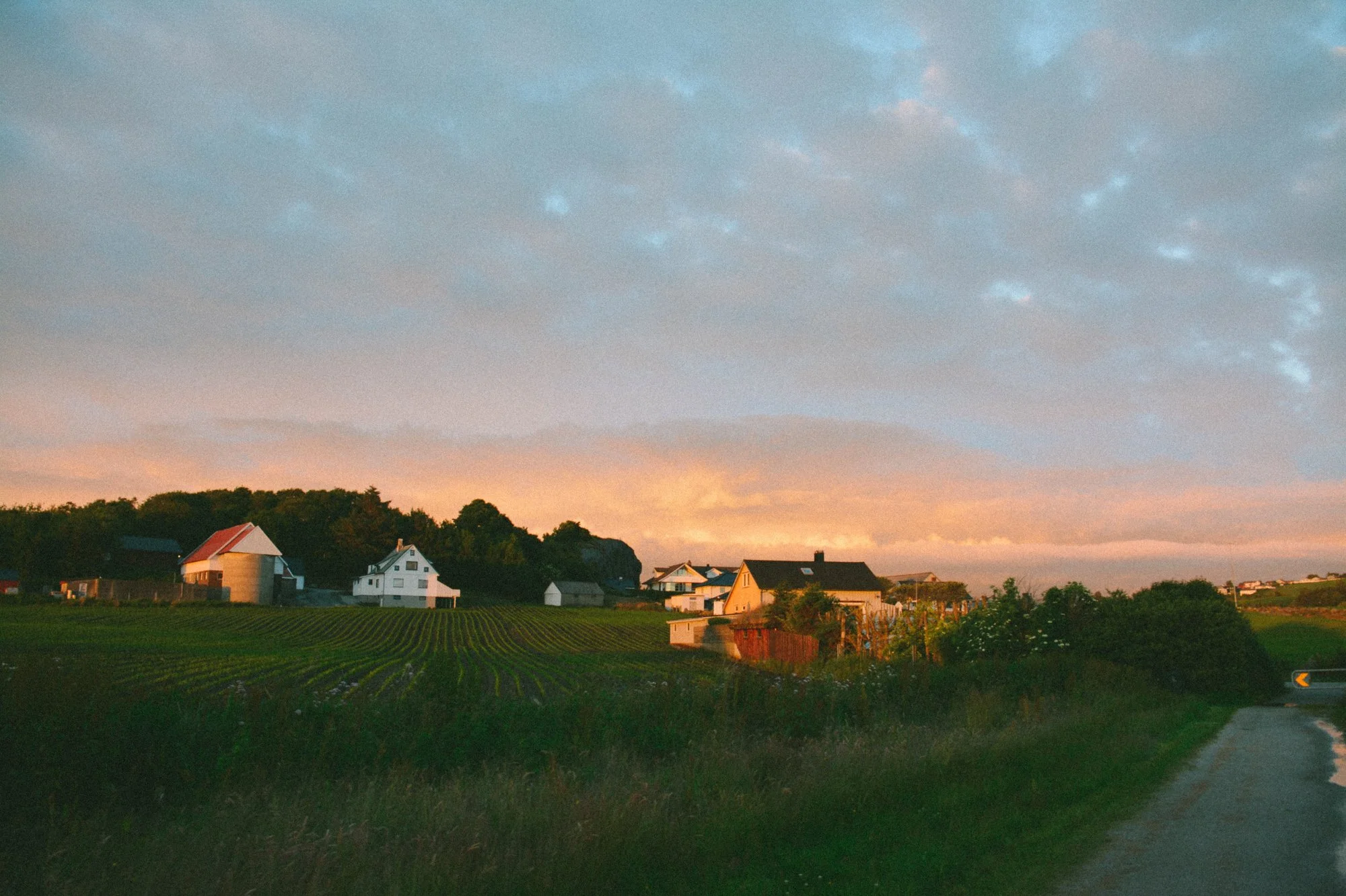 Paysage rural avec des maisons et champs au coucher du soleil.