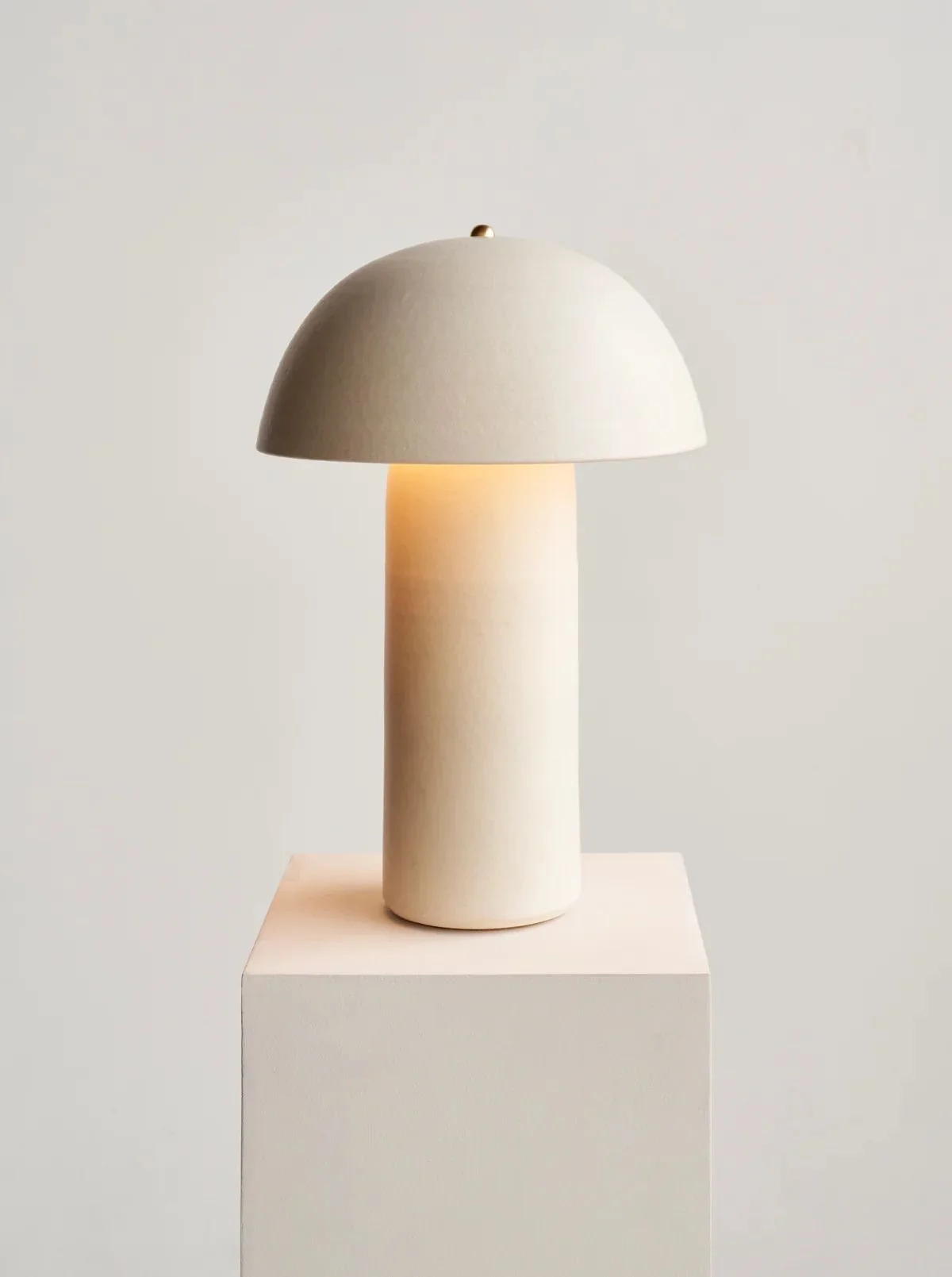 Minimalist table lamp with a dome-shaped shade on a pedestal.