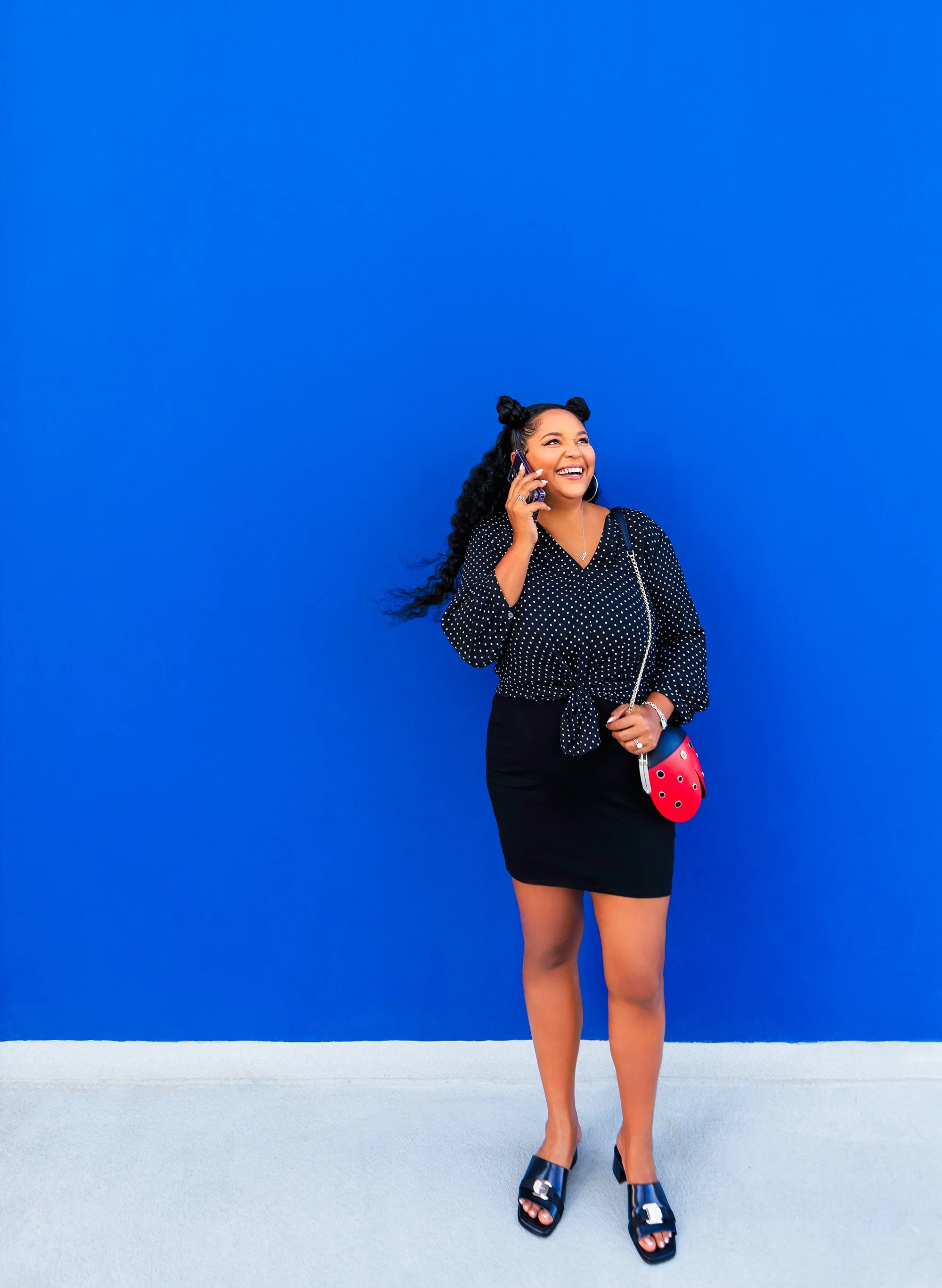 A woman laughing on her phone against a bright blue wall in Jacksonville.