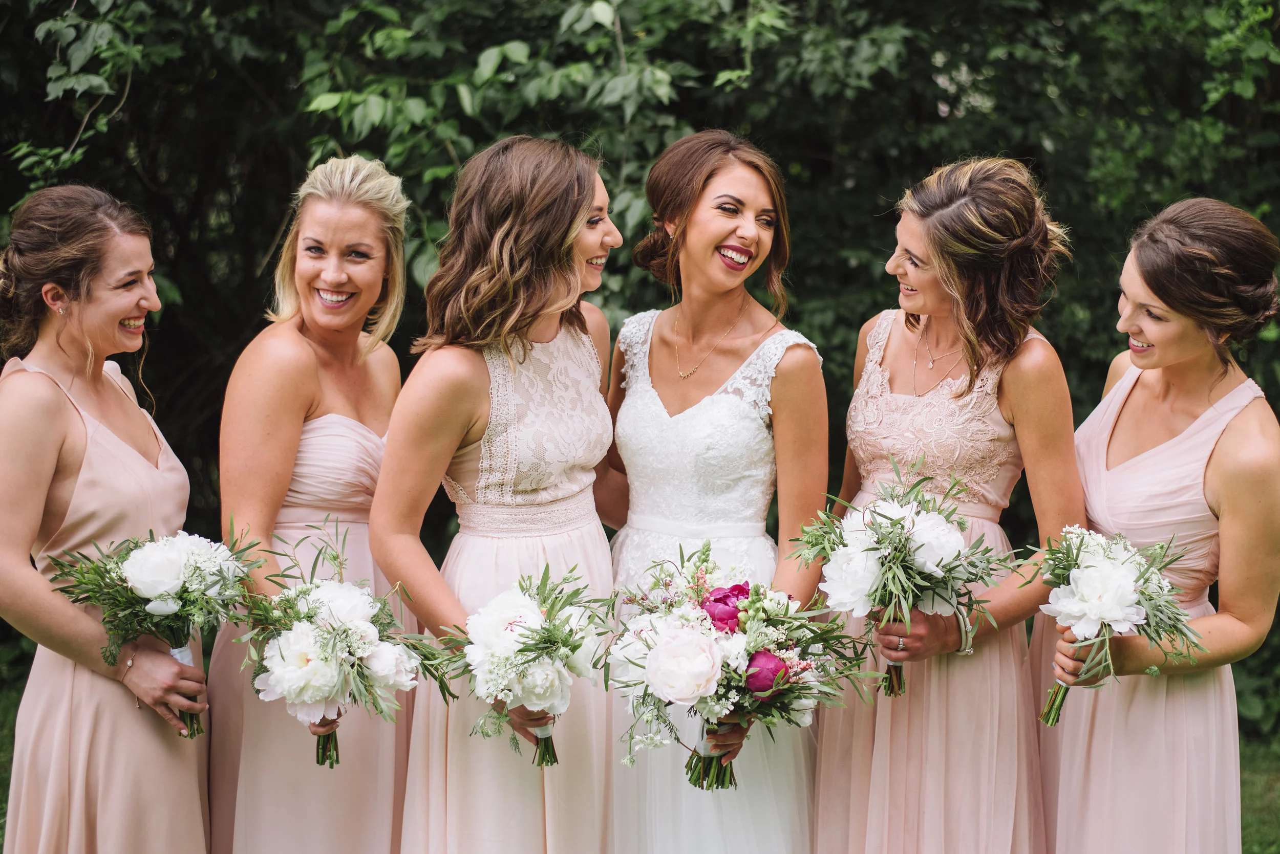 Adding pops of color to the brides bouquet while keeping the bridesmaid’s white and green is a great way to let the bride stand out.
