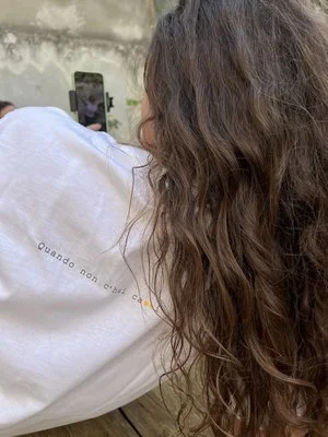 Donna con capelli lunghi ondulati e la maglietta bianca di Polpe, una linea che descrive la punteggiatura.