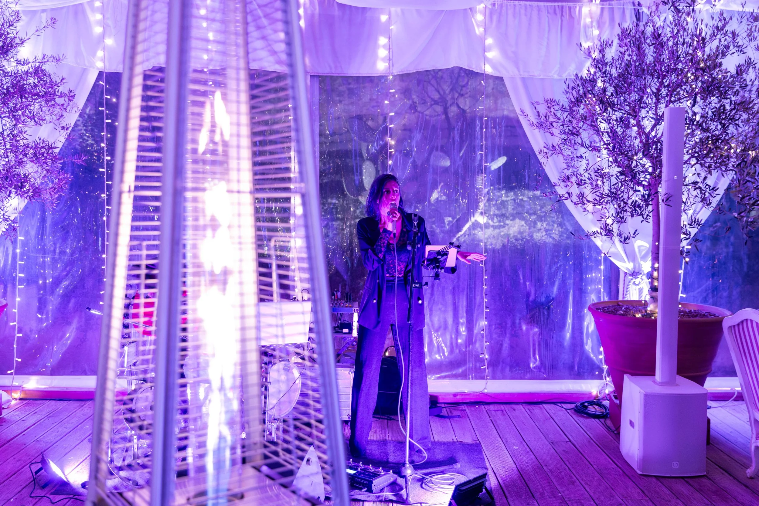 Persona che canta e suona all'interno di una tenda illuminata con luci viola.