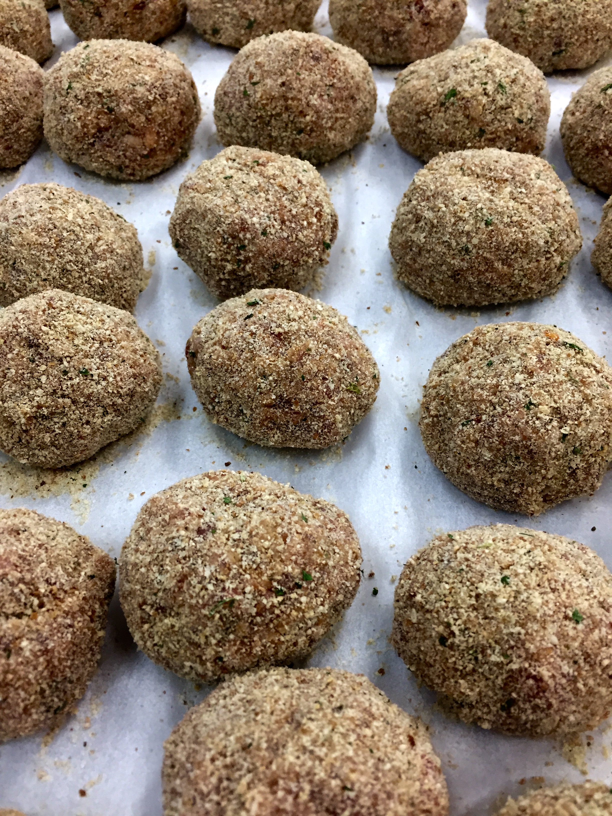 Hand-rolled meatballs breaded and ready to fry.