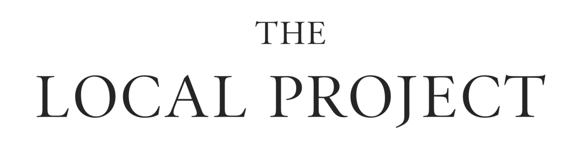 The image is a black and white logo for 'The Local Project.' The words are arranged with 'The' above the larger 'Local Project,' all in a serif font.