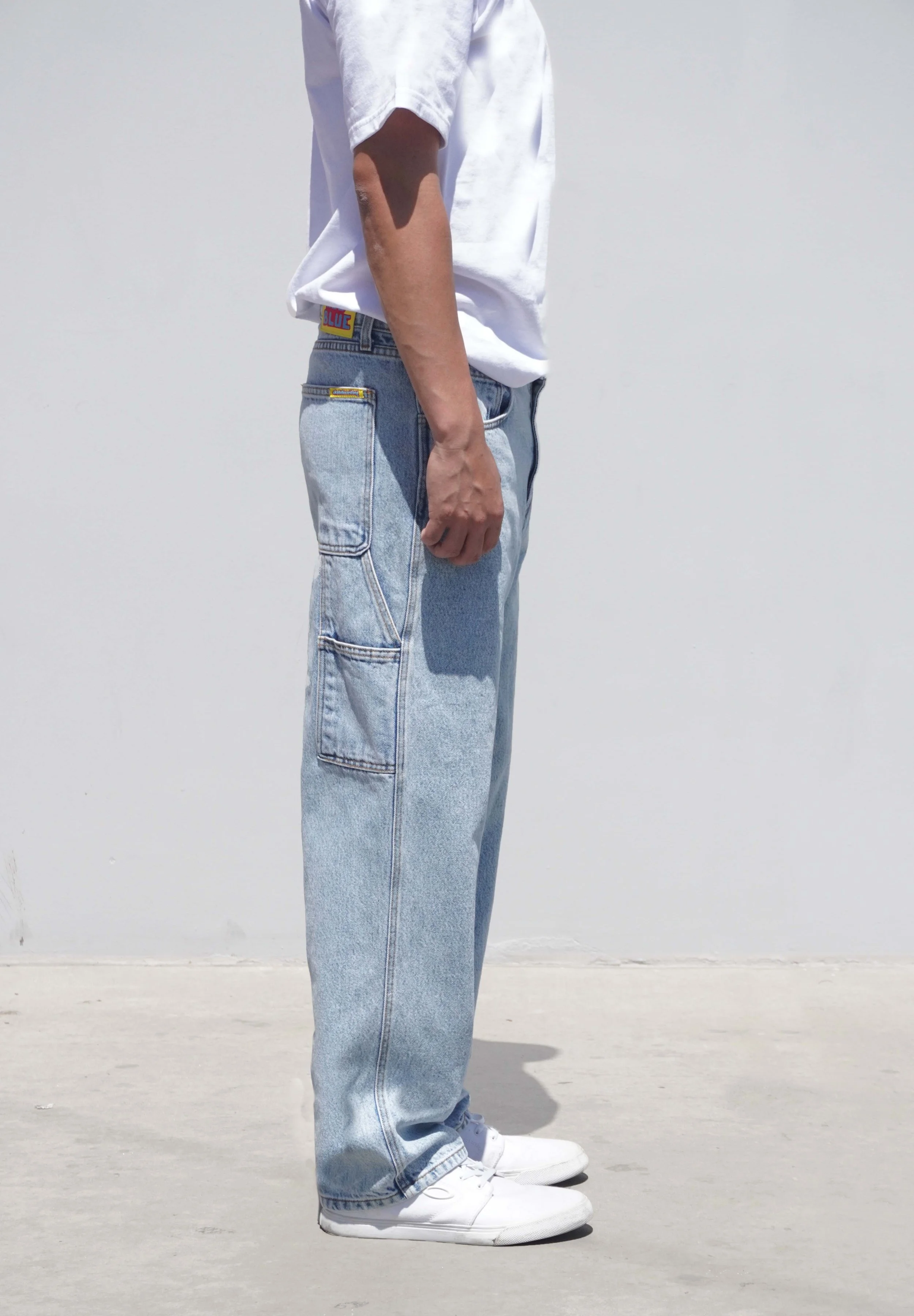Side view of model in pastel blue denim baggy carpenter jeans.