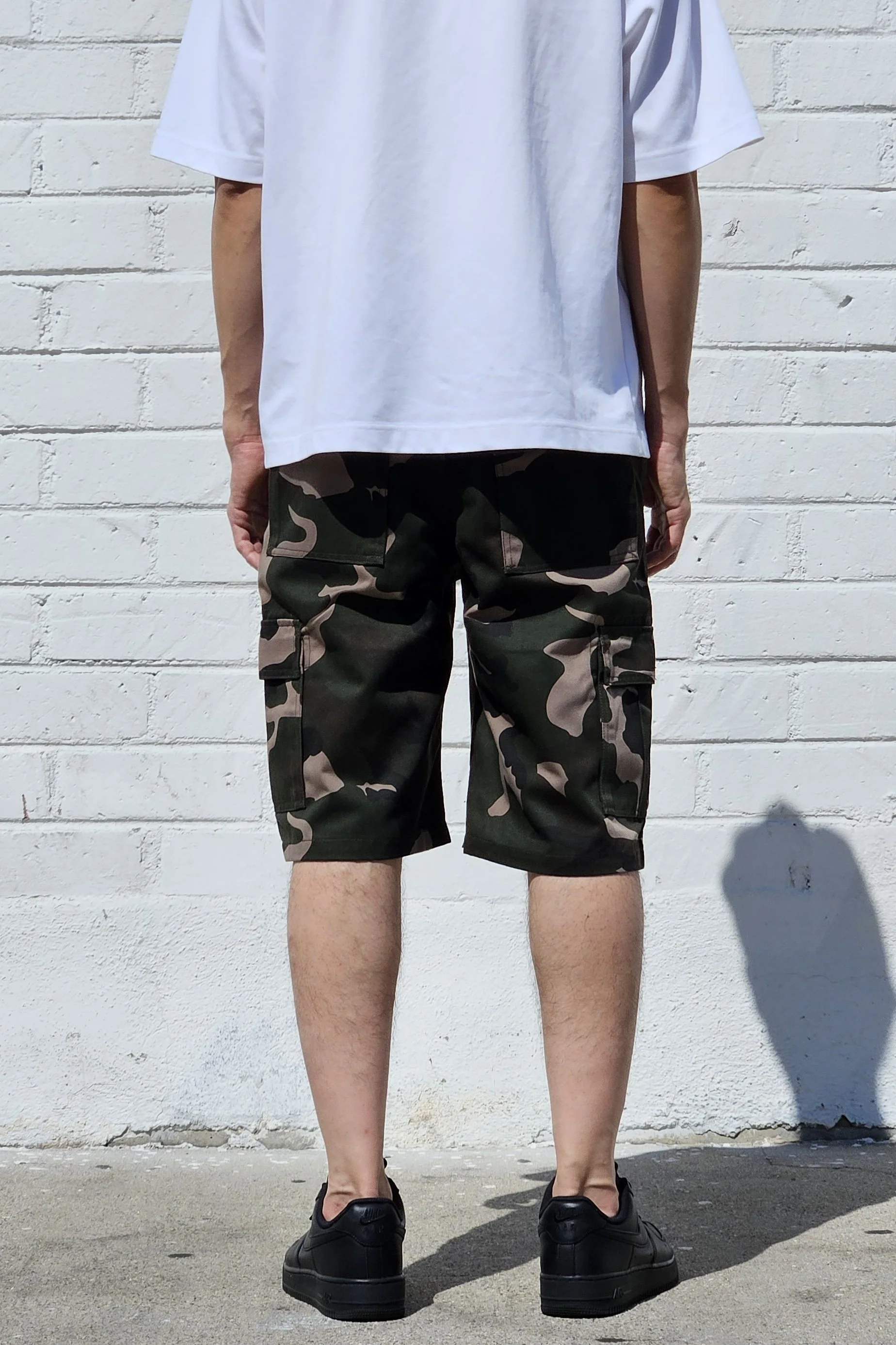 Back view of model in camo green cargo baggy shorts.