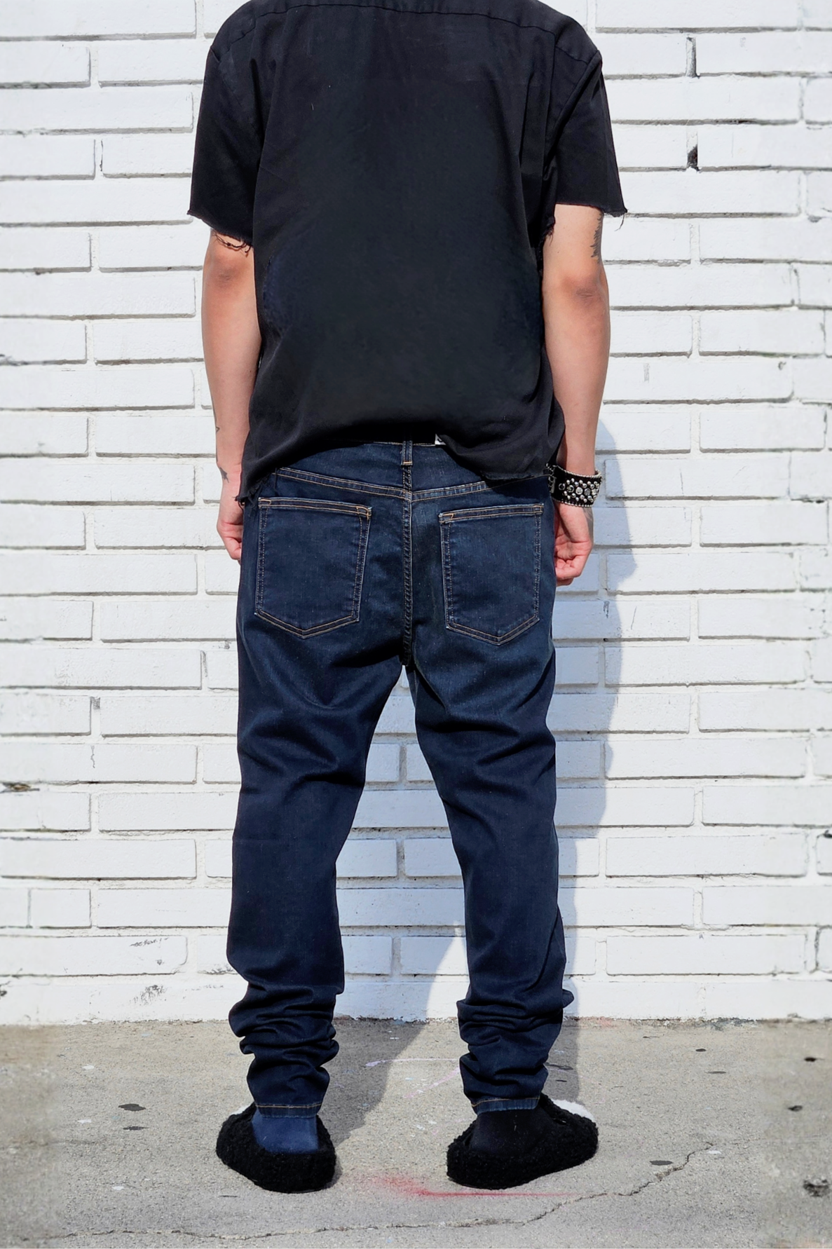 Back view of model in fade dark indigo super skinny jeans for men in modern streetstyle.