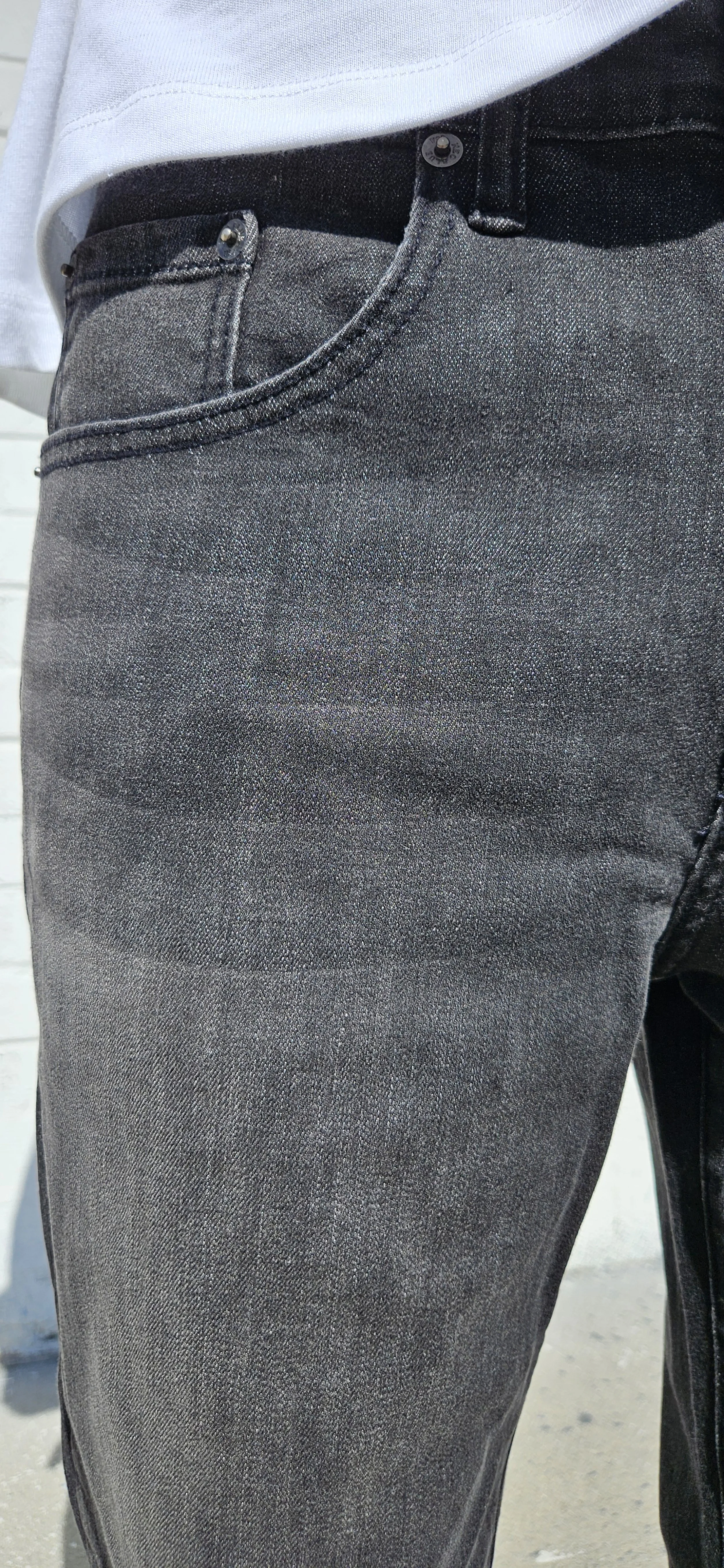 Detail view of model in mens relaxed jeans in fade black denim.