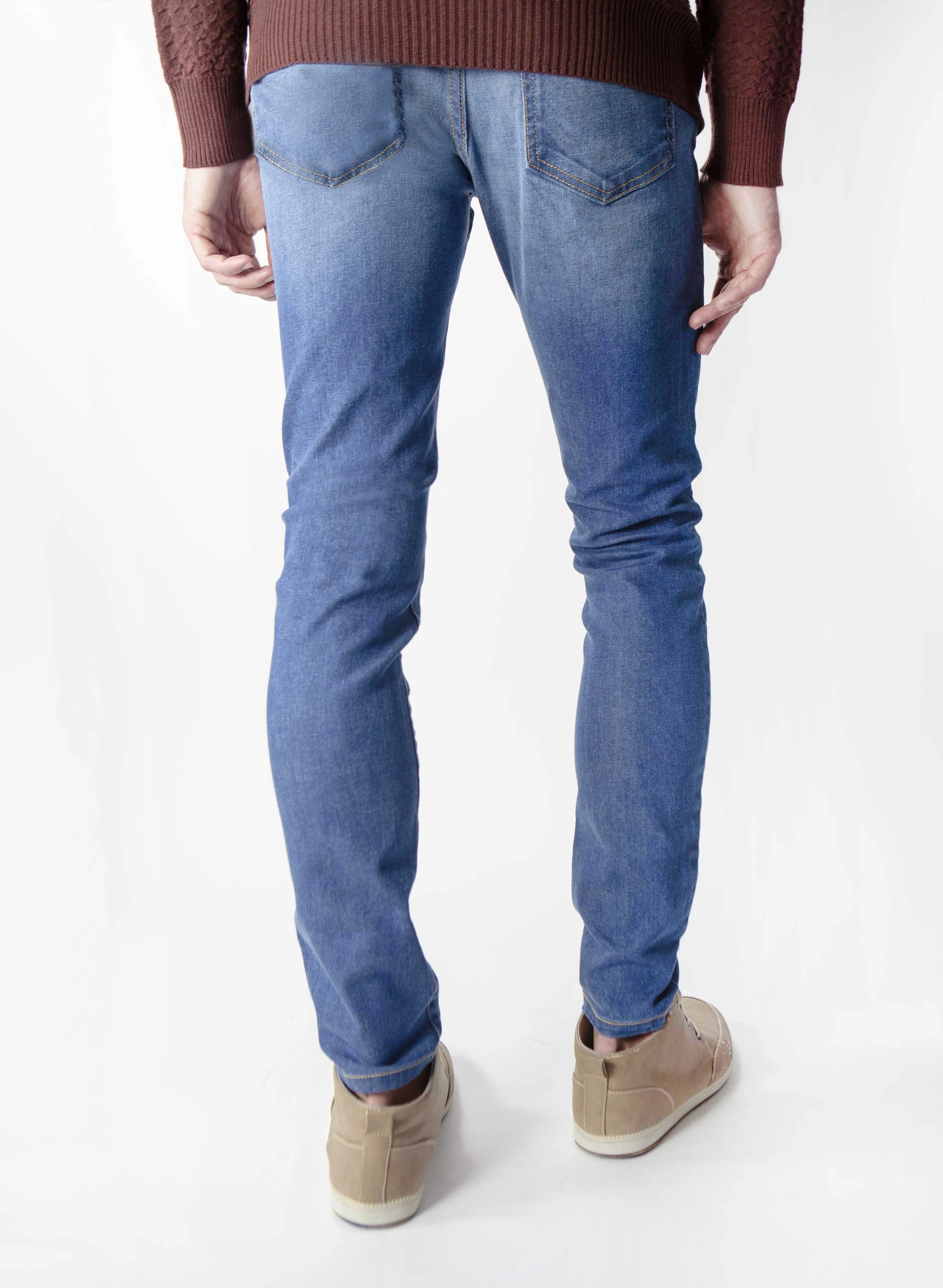 Back view of model in men’s fade medium blue skinny jeans.