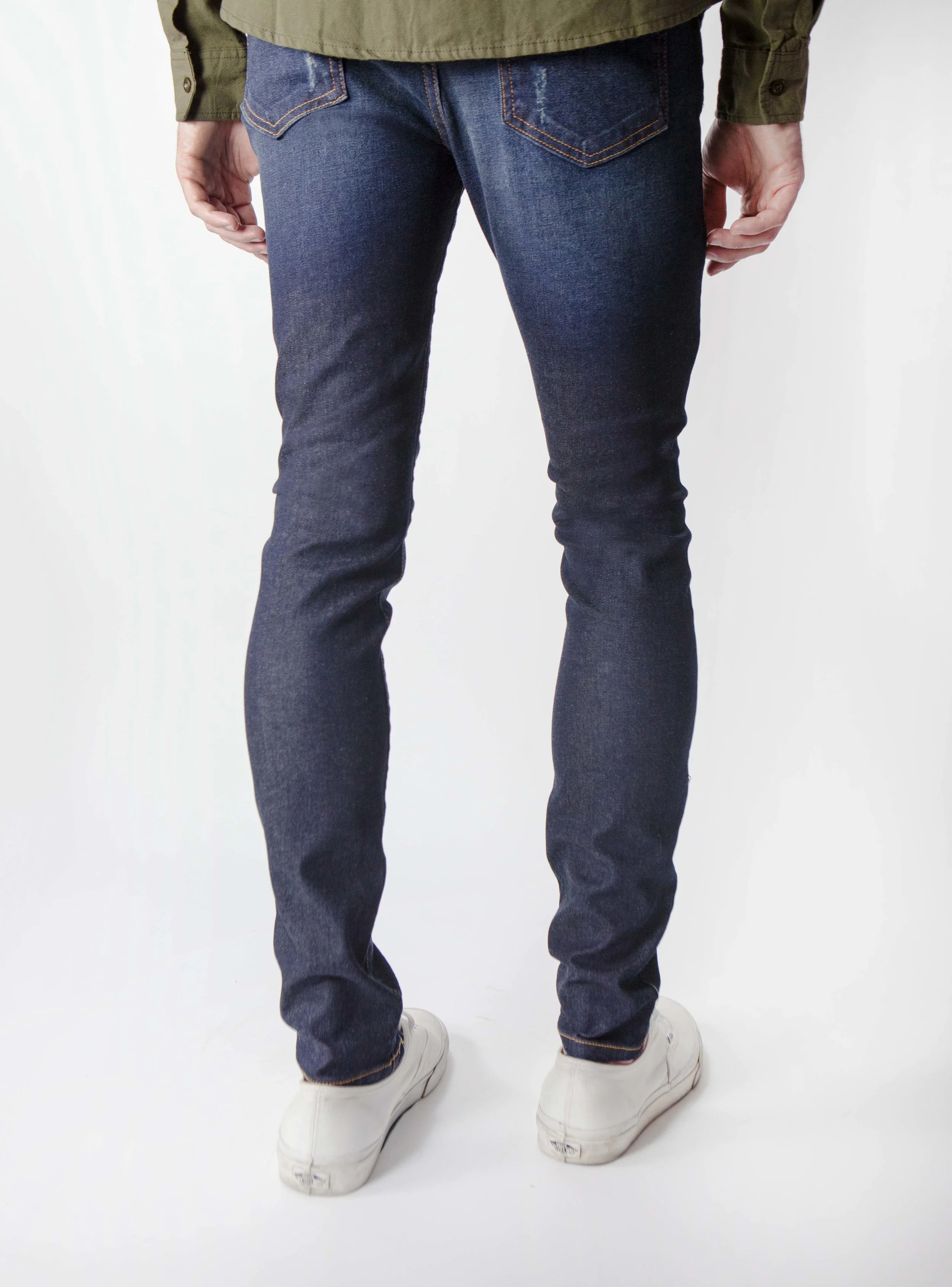 Back view of model in men’s indigo blue ripped skinny jeans.