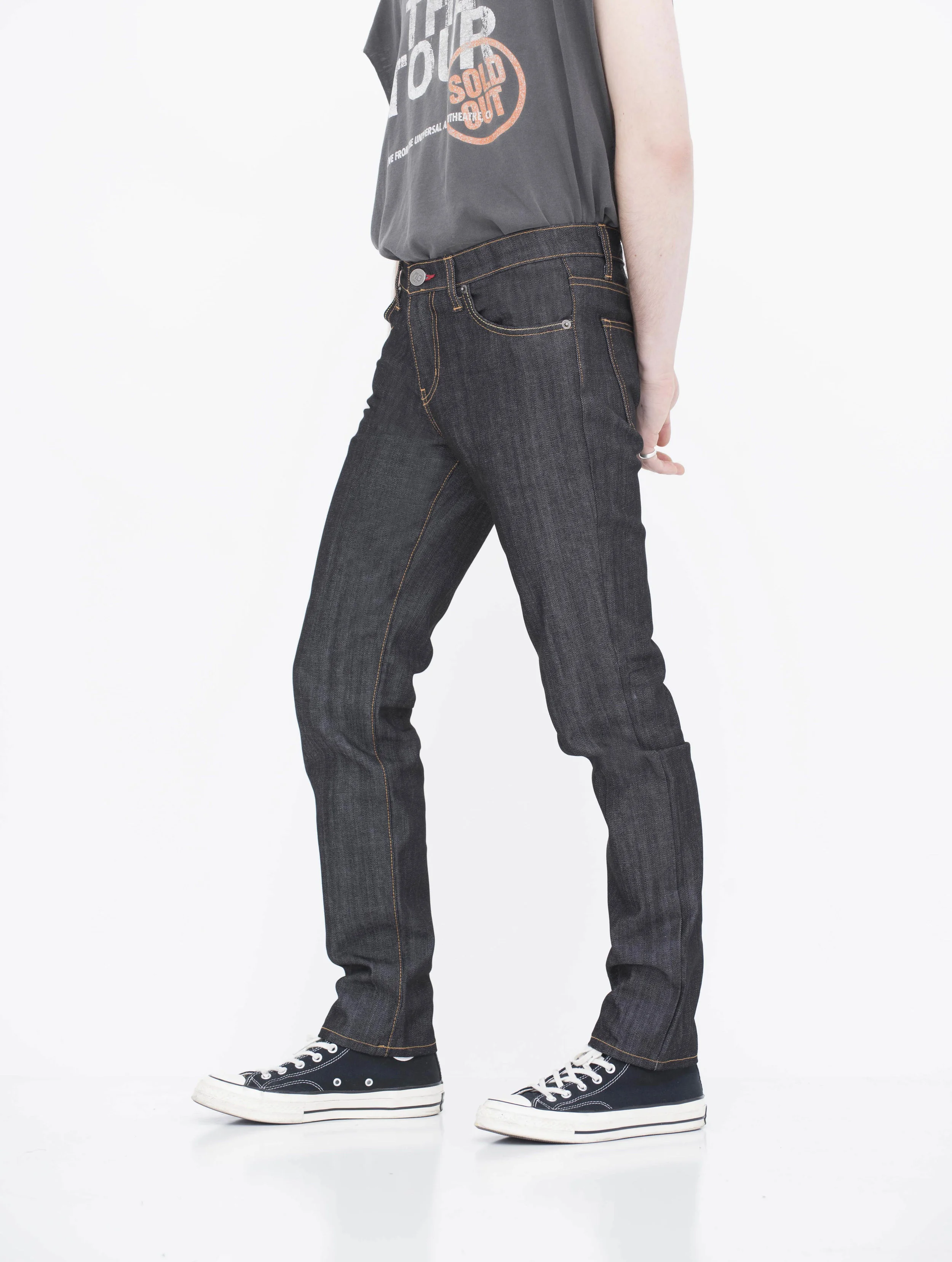 Side view of model indigo black gold stitch skinny jeans.