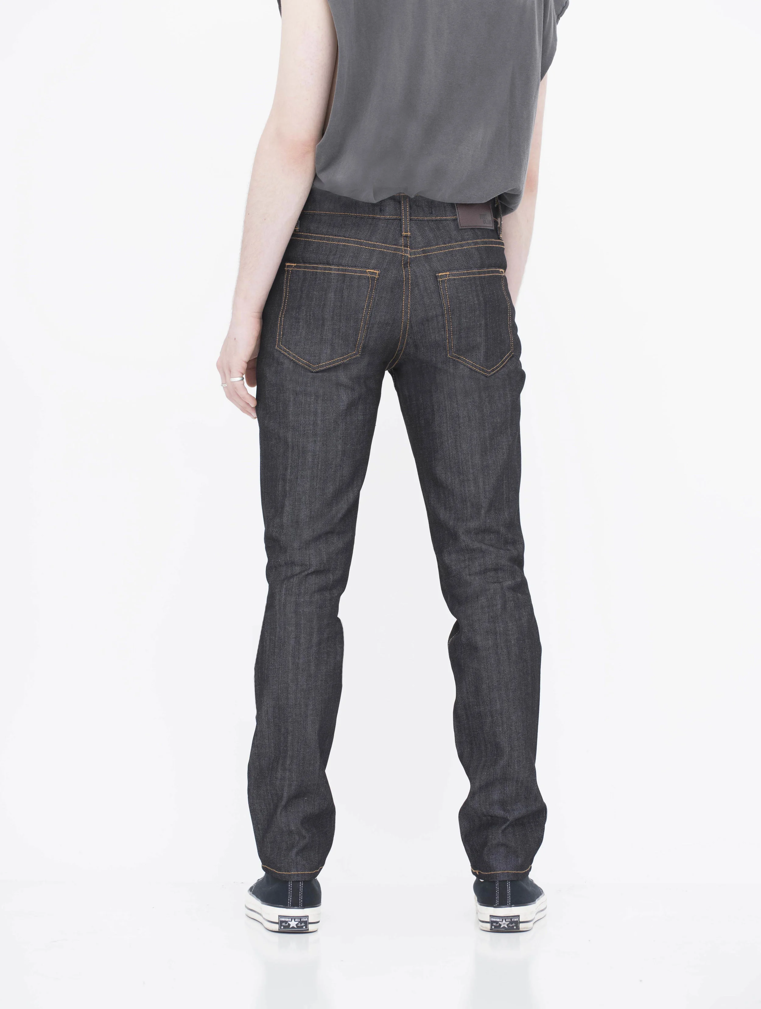 Back view of model indigo black gold stitch skinny jeans.