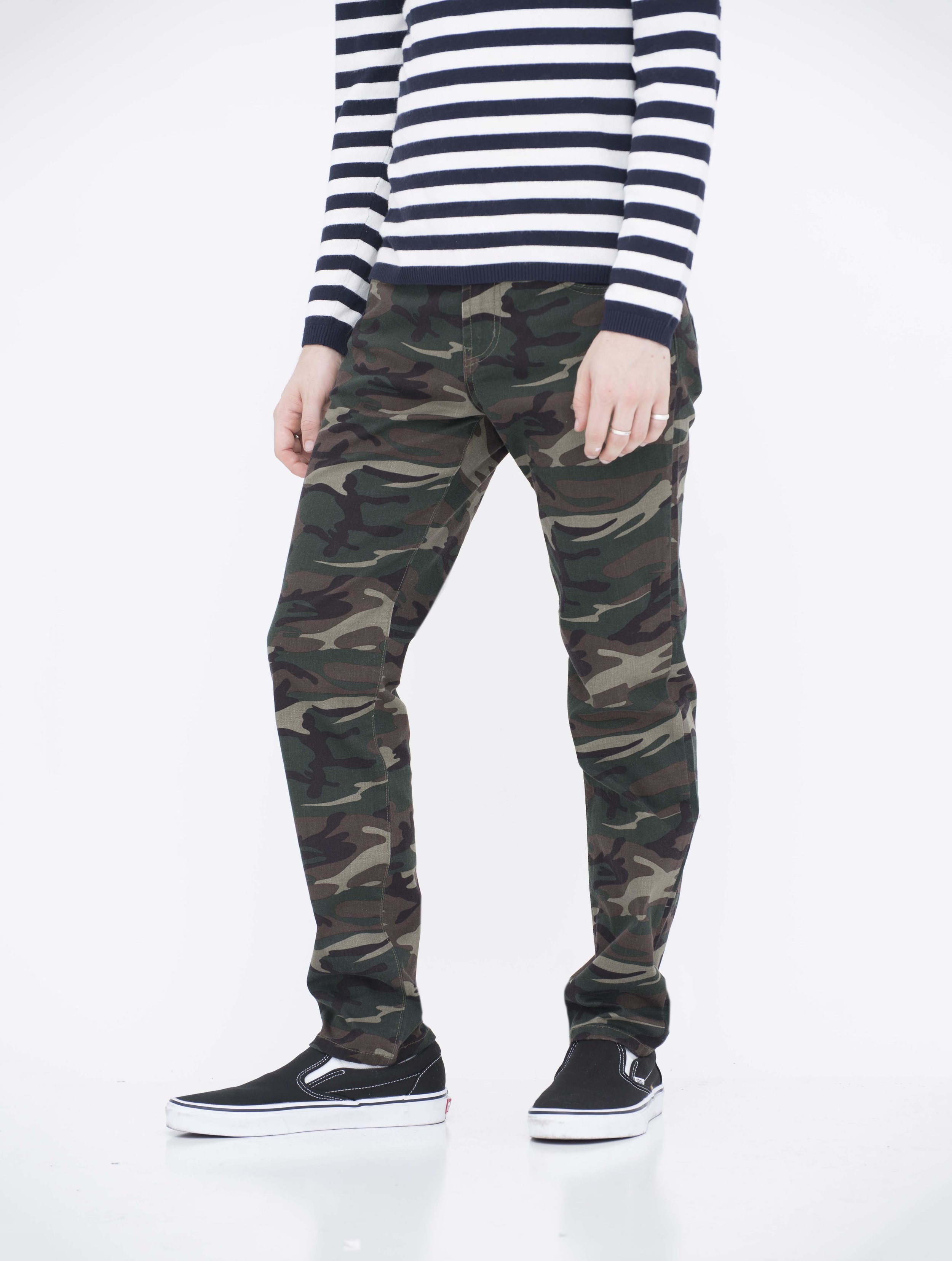 Side view of model in neo blue camo green skinny jeans.