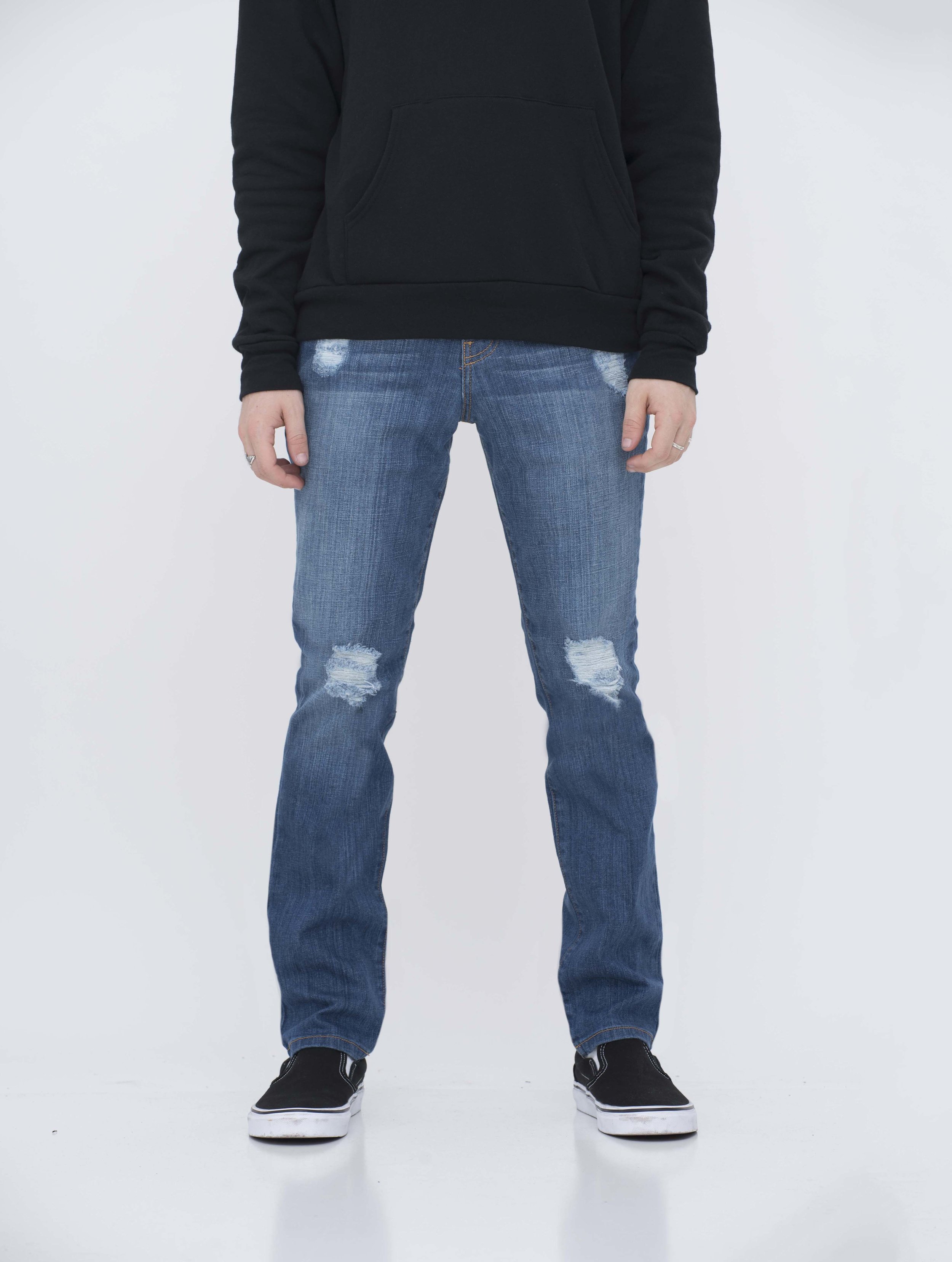 Front view of model in ripped medium blue skinny jeans.
