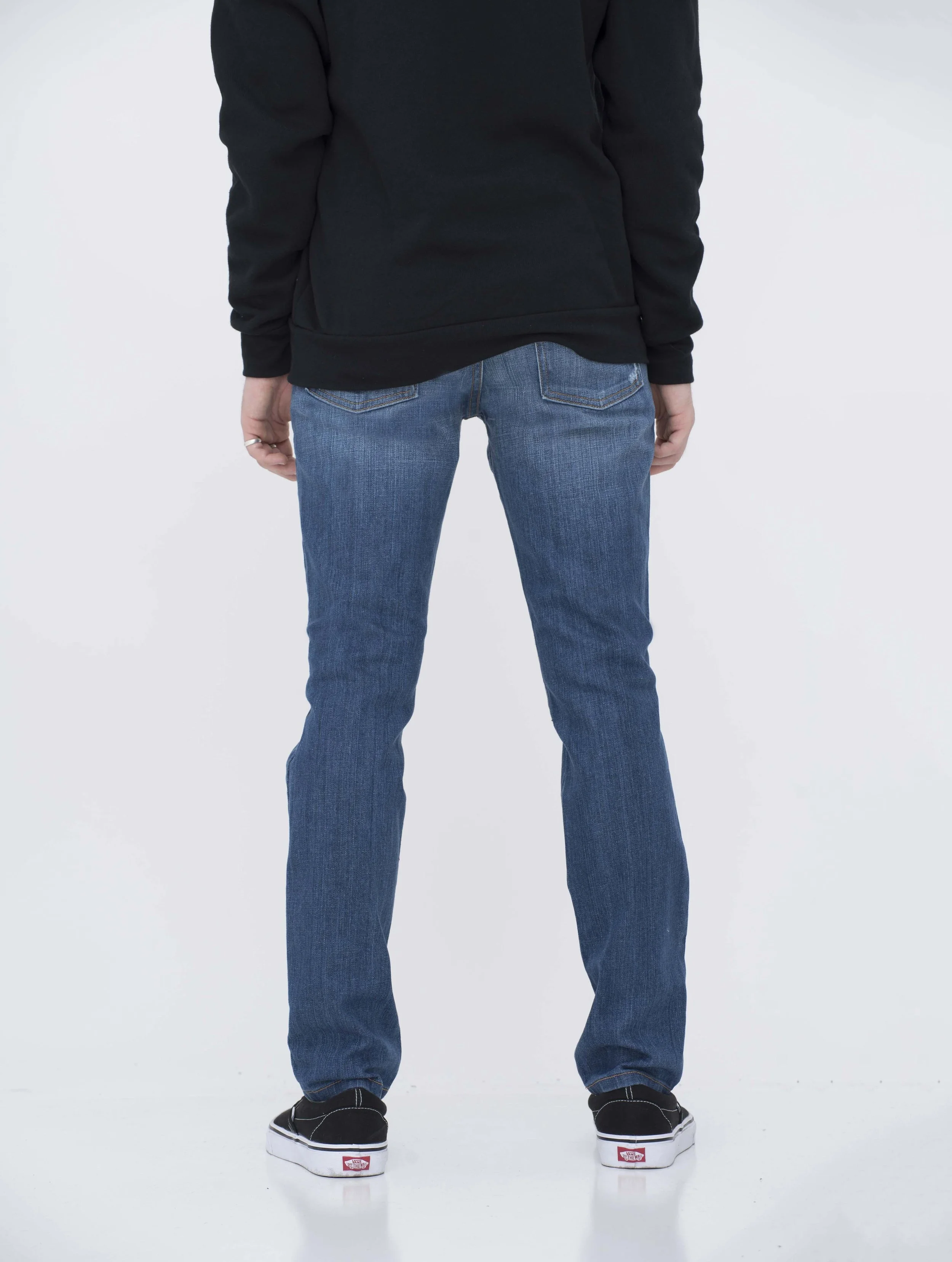 Back view of model in ripped medium blue skinny jeans.