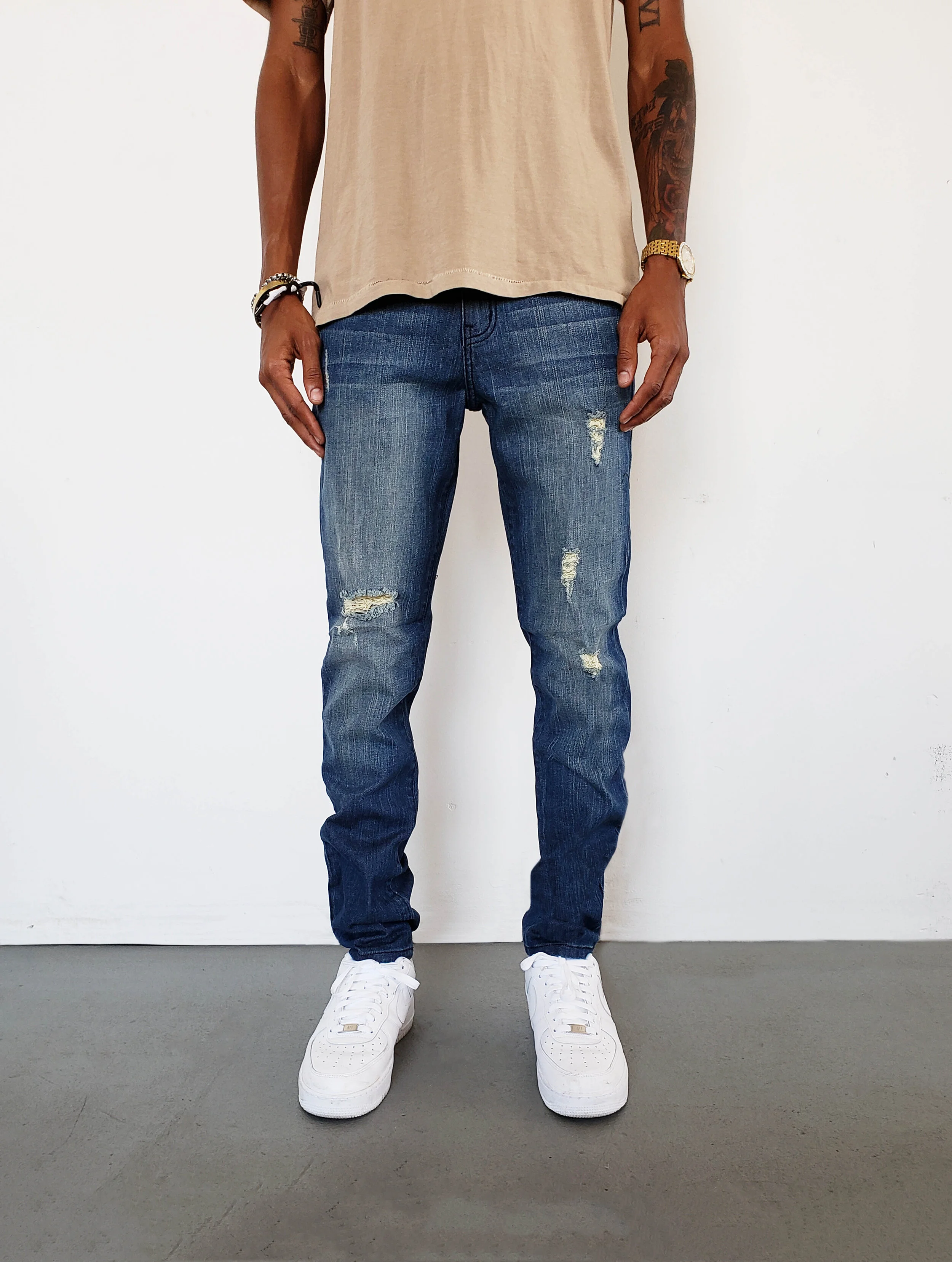 Front view of model in ripped tinted navy skinny jeans.