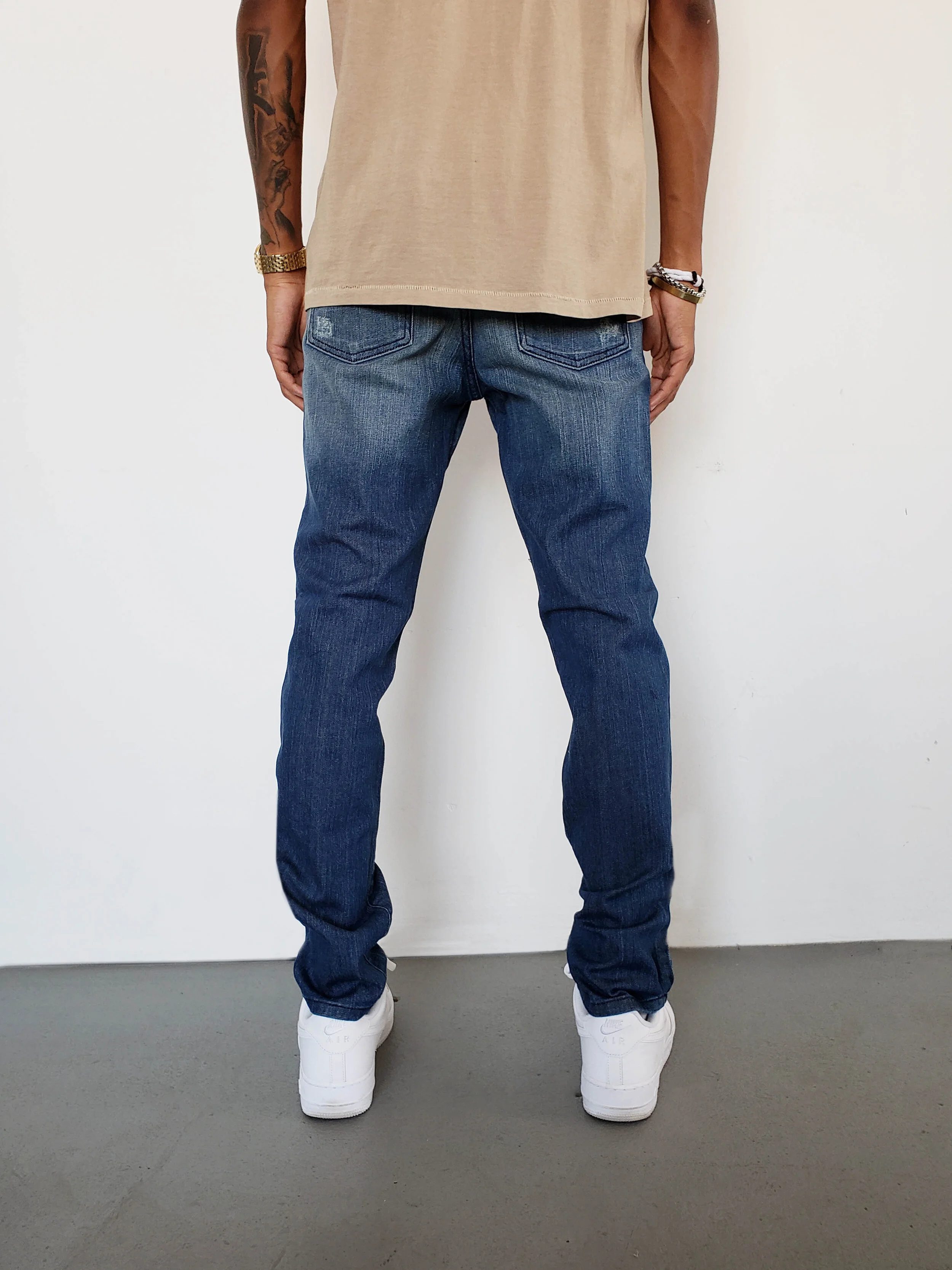 Back view of model in ripped tinted navy skinny jeans.
