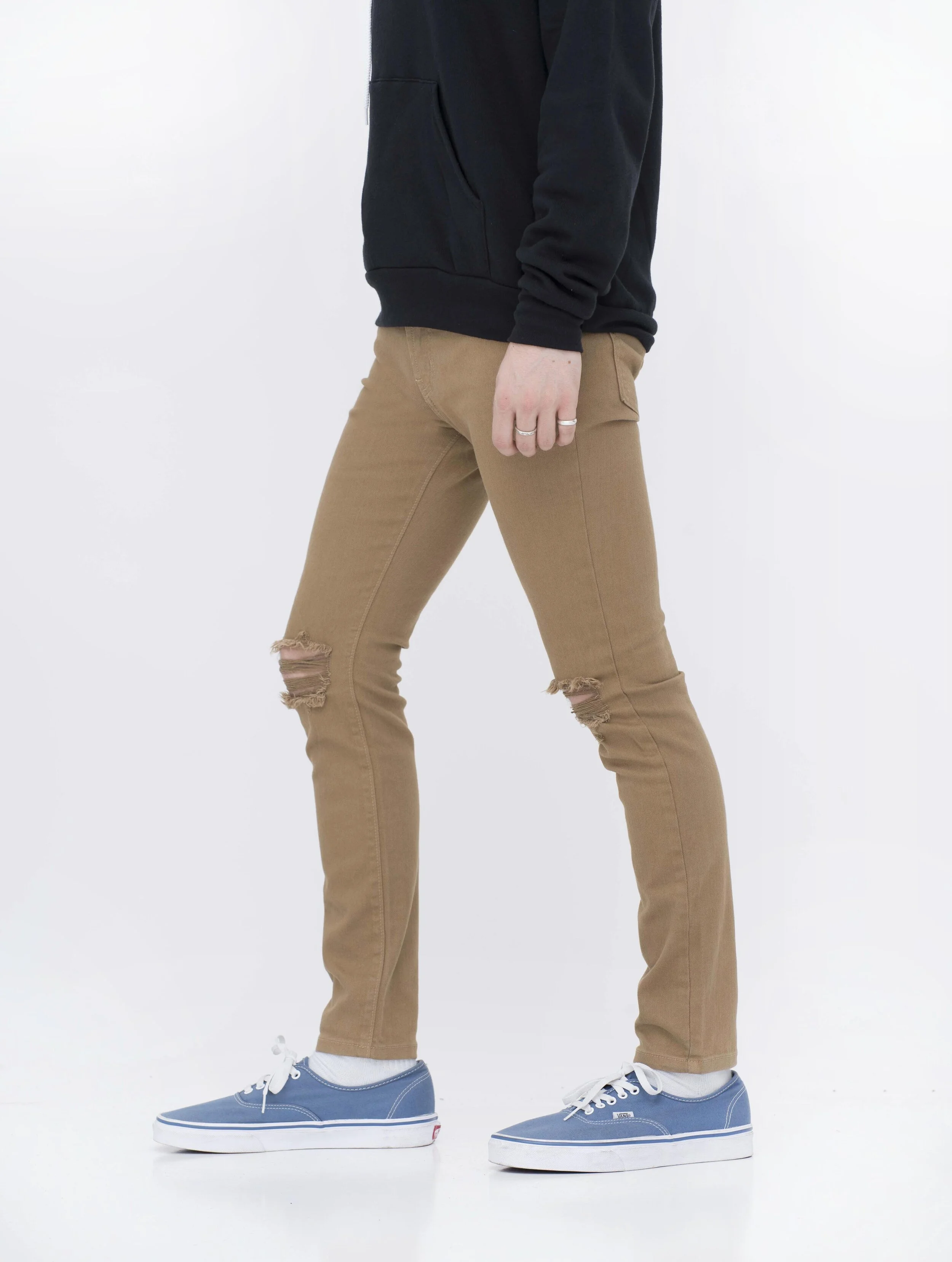 Side view of model in men’s knee ripped camel skinny jeans.