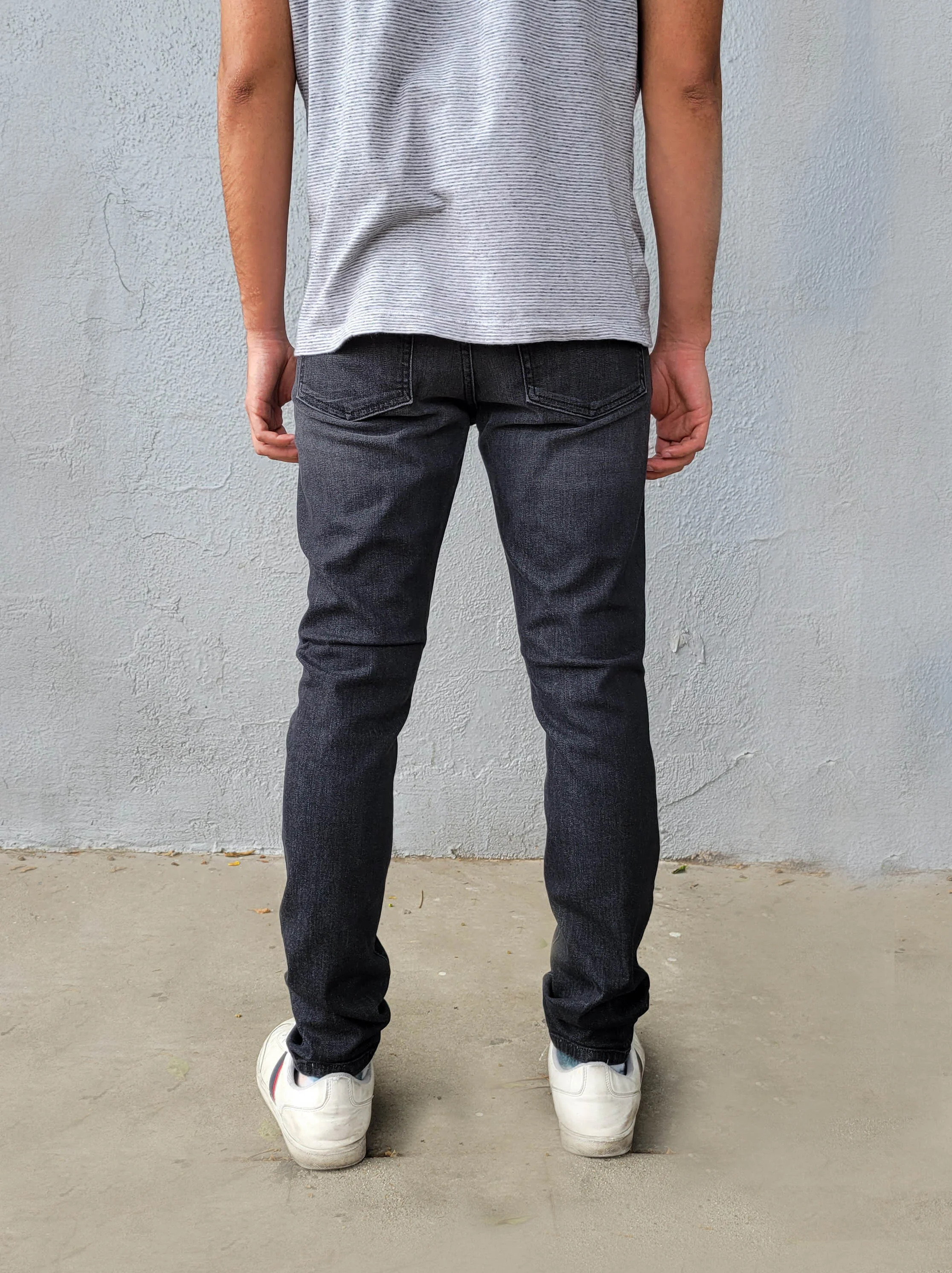 Back view of model in fade black super skinny jeans.