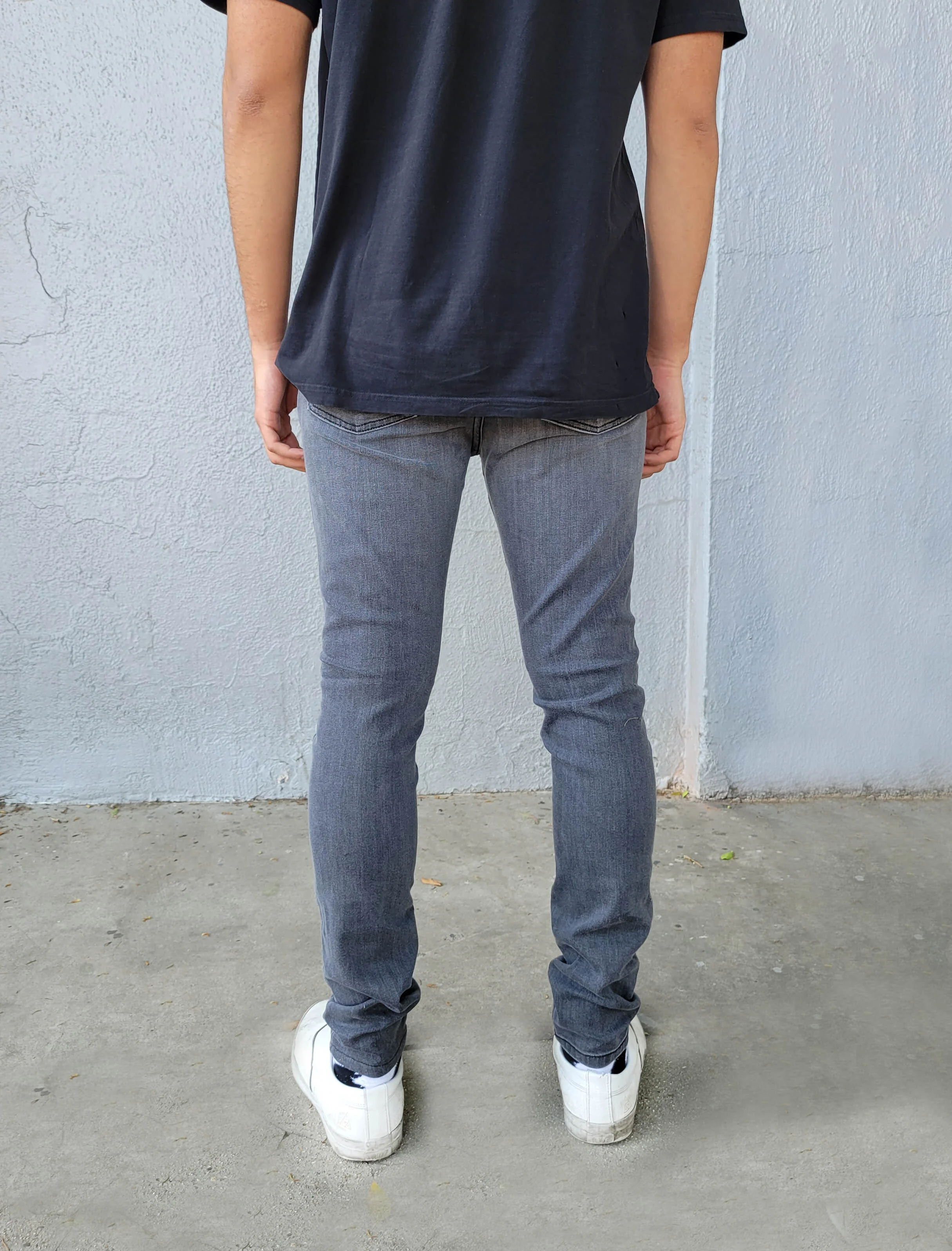 Back view of model in men’s charcoal fade skinny jeans.