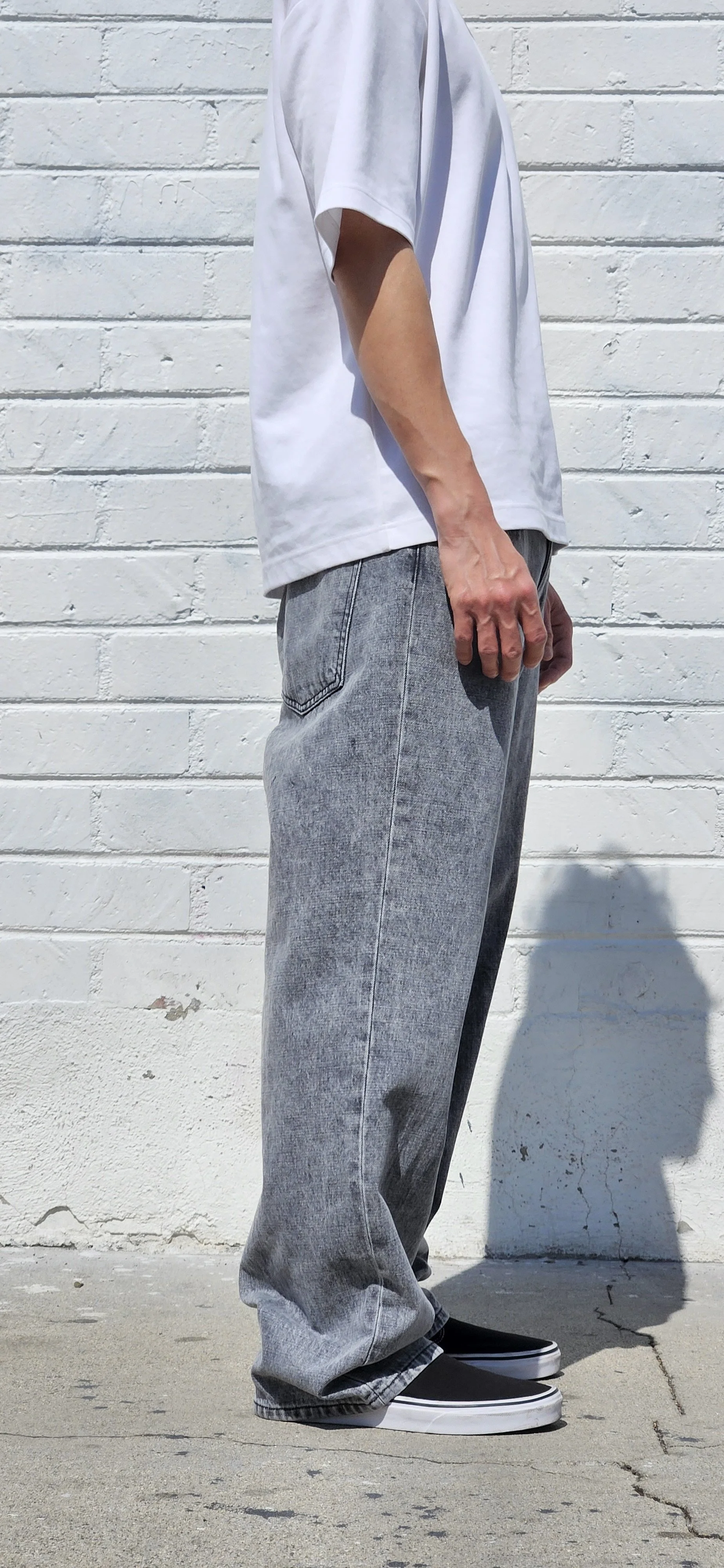 Side view of model in acid black denim baggy jeans.