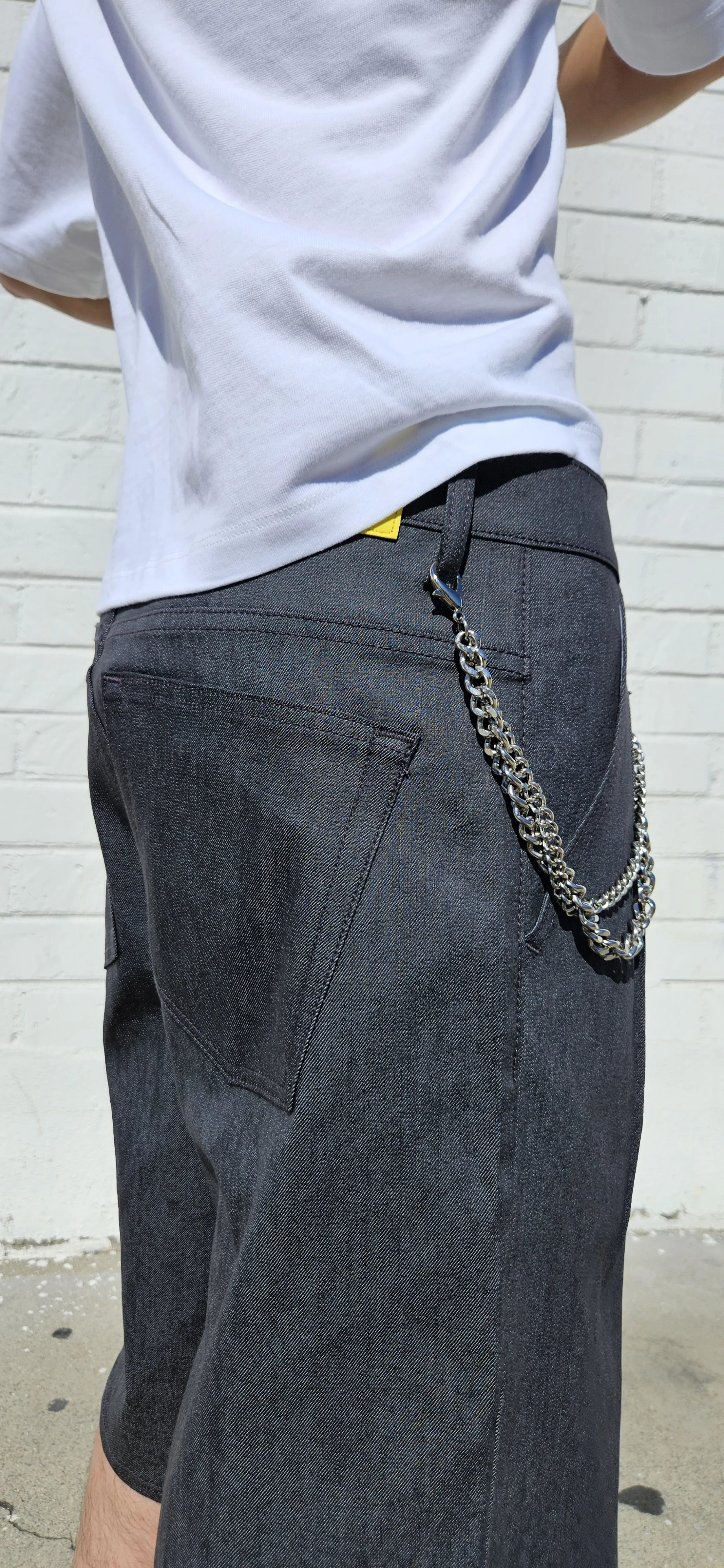 Close up back view of denim charcoal double pleated baggy jeans short with chain belt