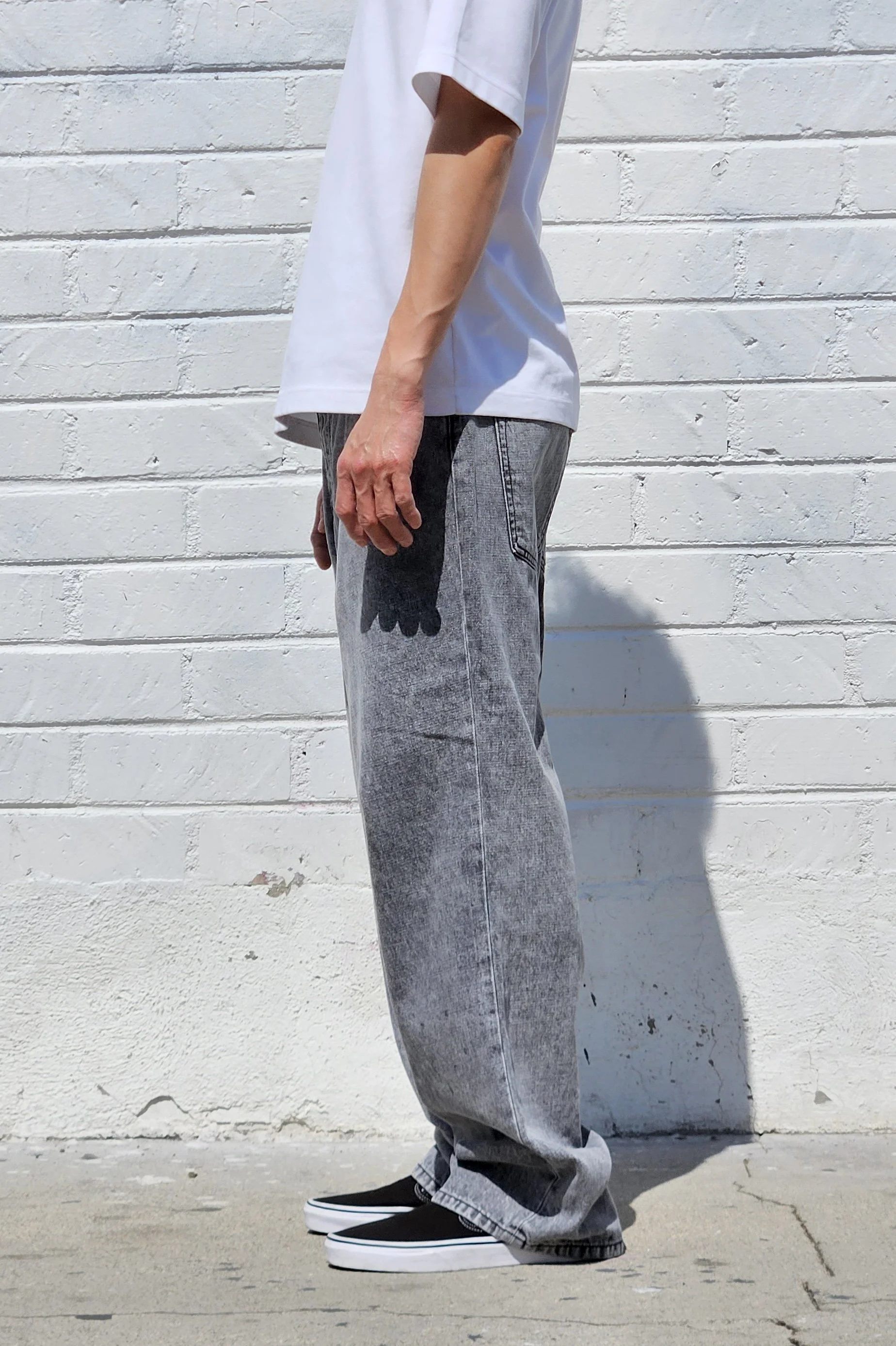 Side view of model in acid black denim baggy jeans.