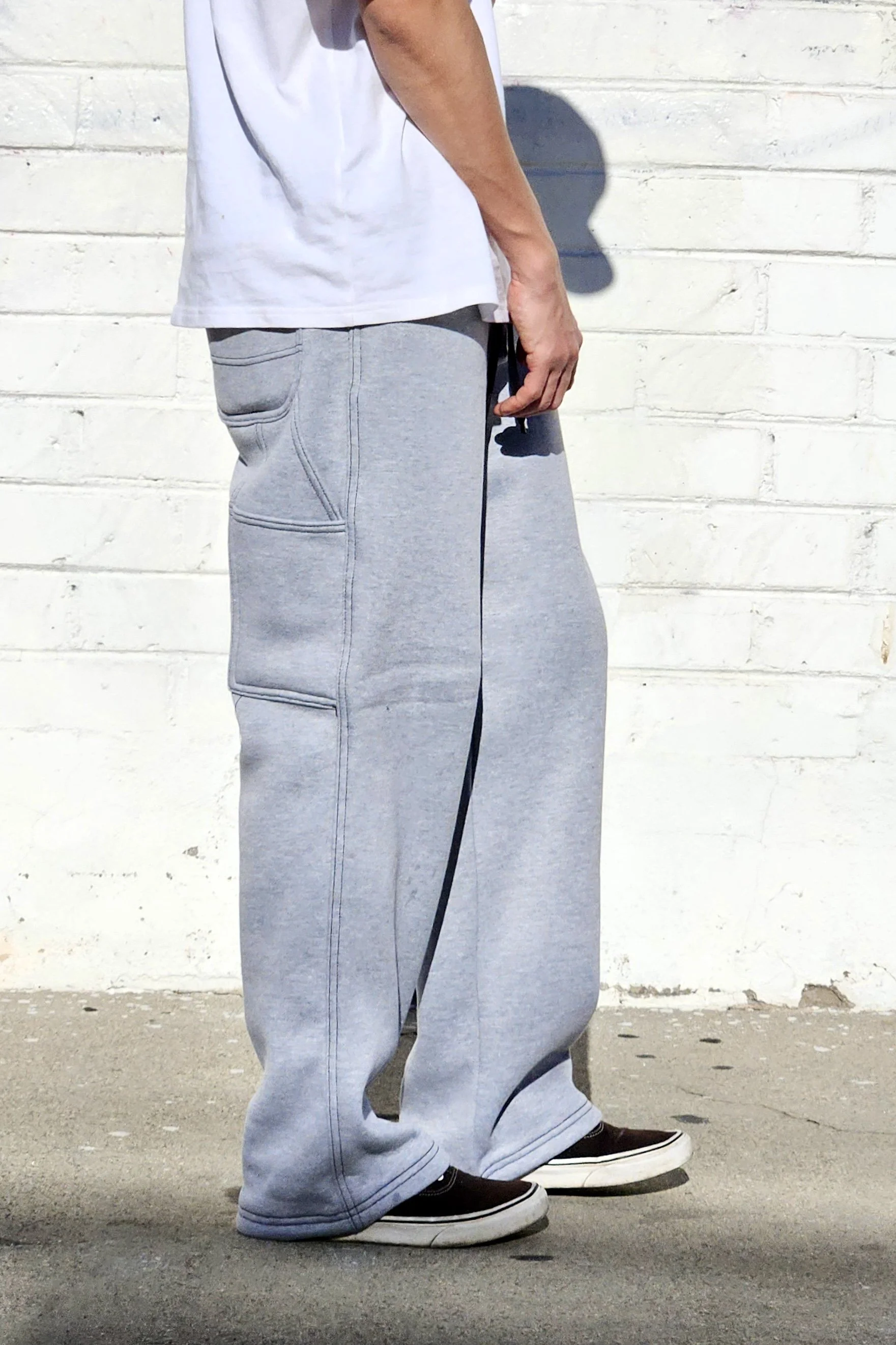 Side view of model in unisex grey baggy carpenter sweatpants.