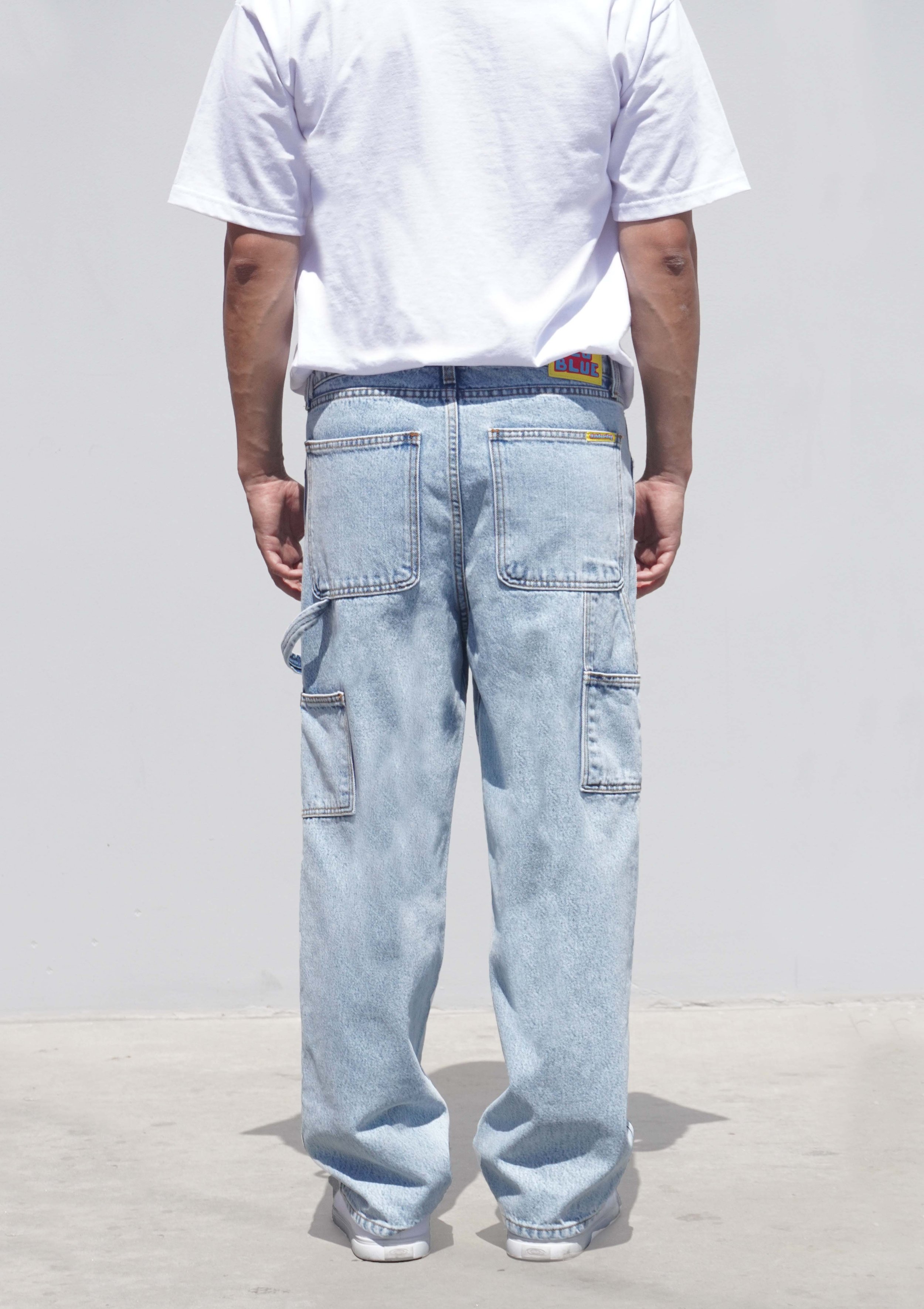Back view of model in pastel blue denim baggy carpenter jeans.