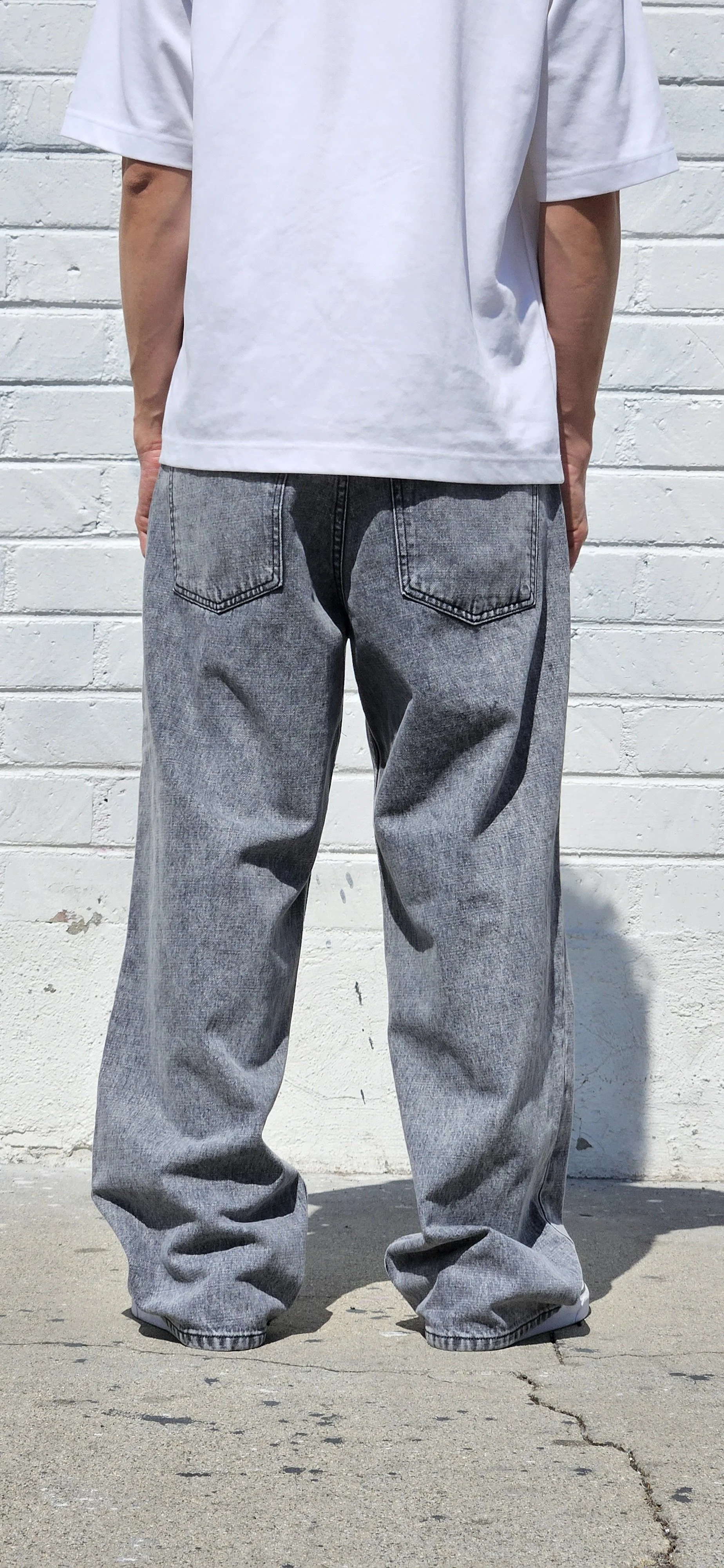 Back view of model in acid black denim baggy jeans.