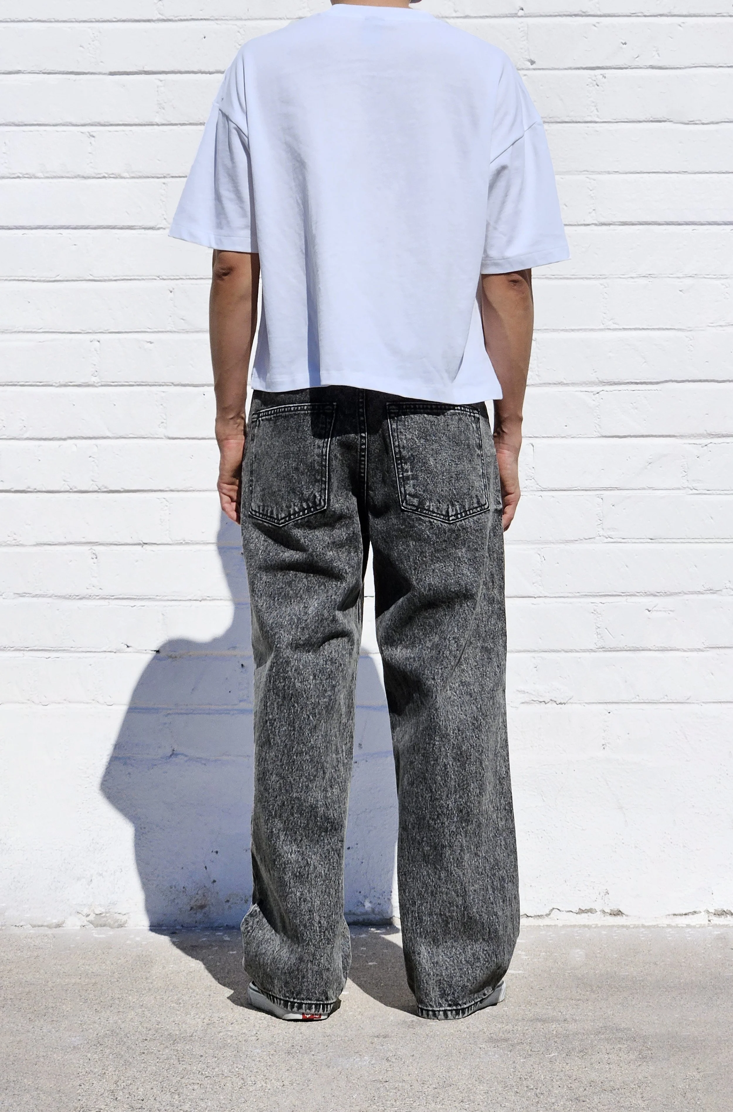 Back view of model in dark acid black baggy jeans.