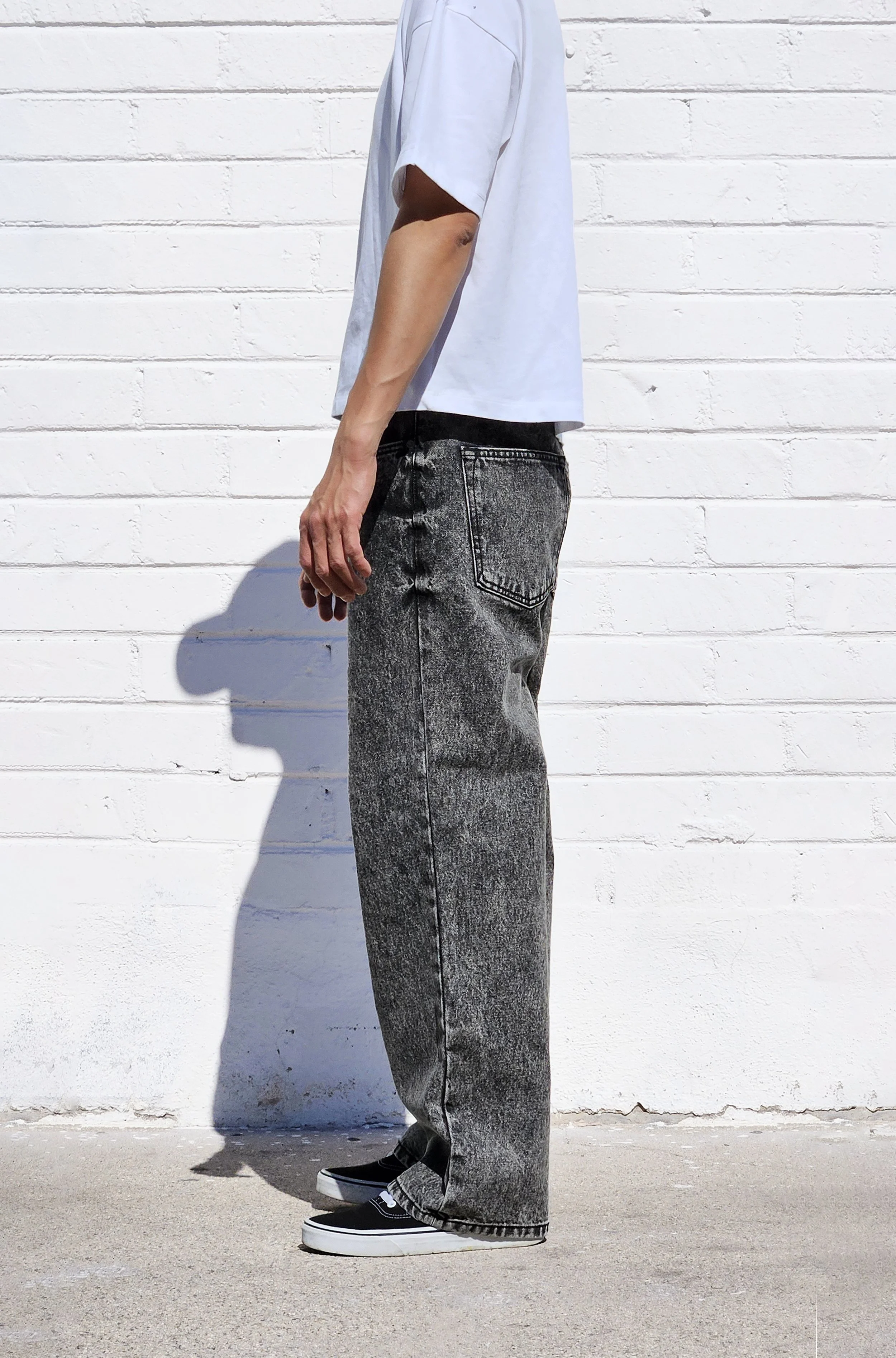 Side view of model in dark acid black baggy jeans.