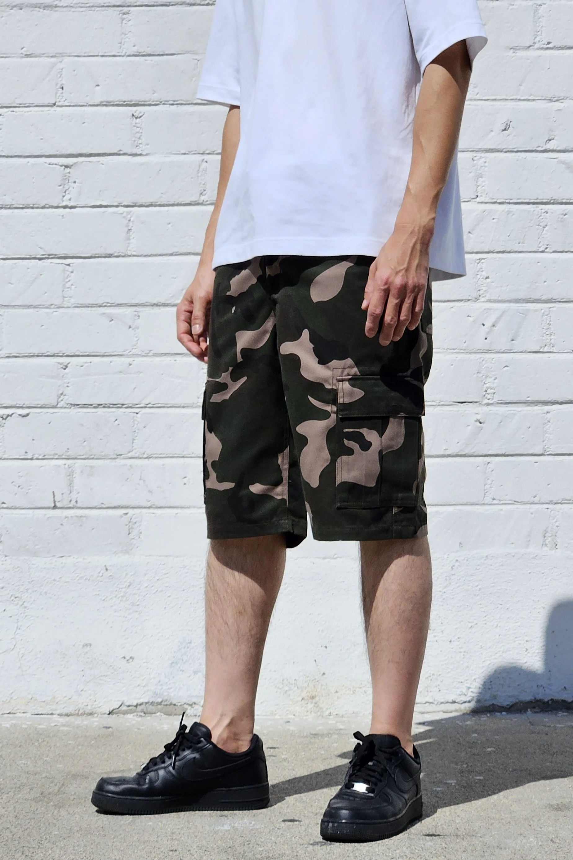 Side view of model in camo green cargo baggy shorts.