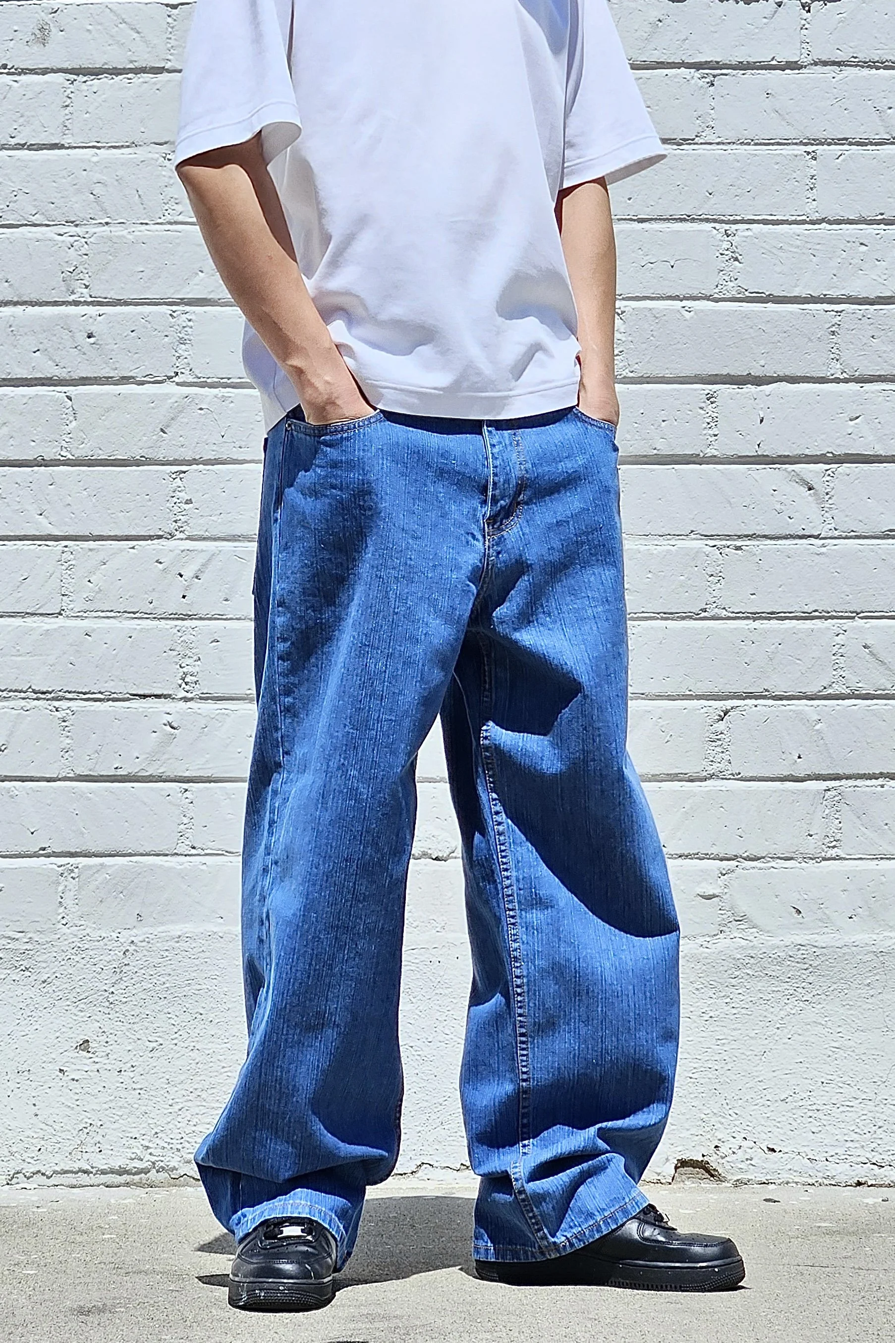 Front view of model in men’s medium blue baggy slub denim jeans.