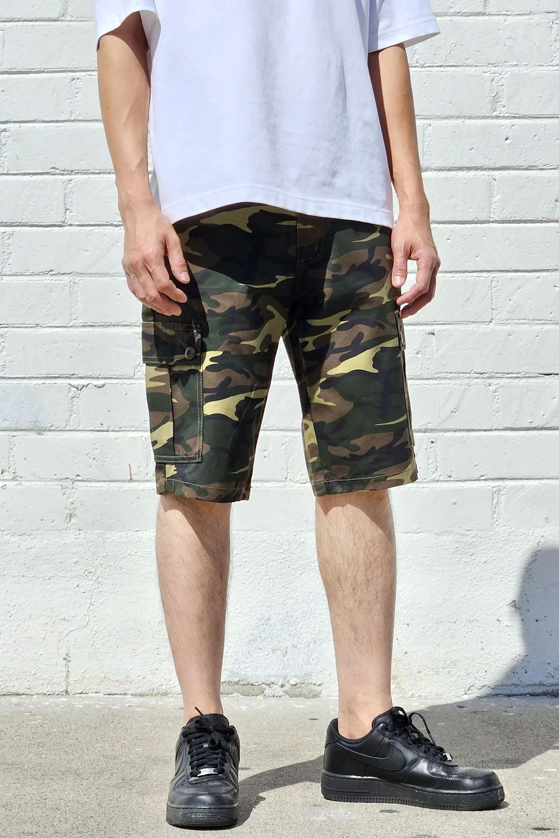 Front view of model in army green camo cargo shorts.