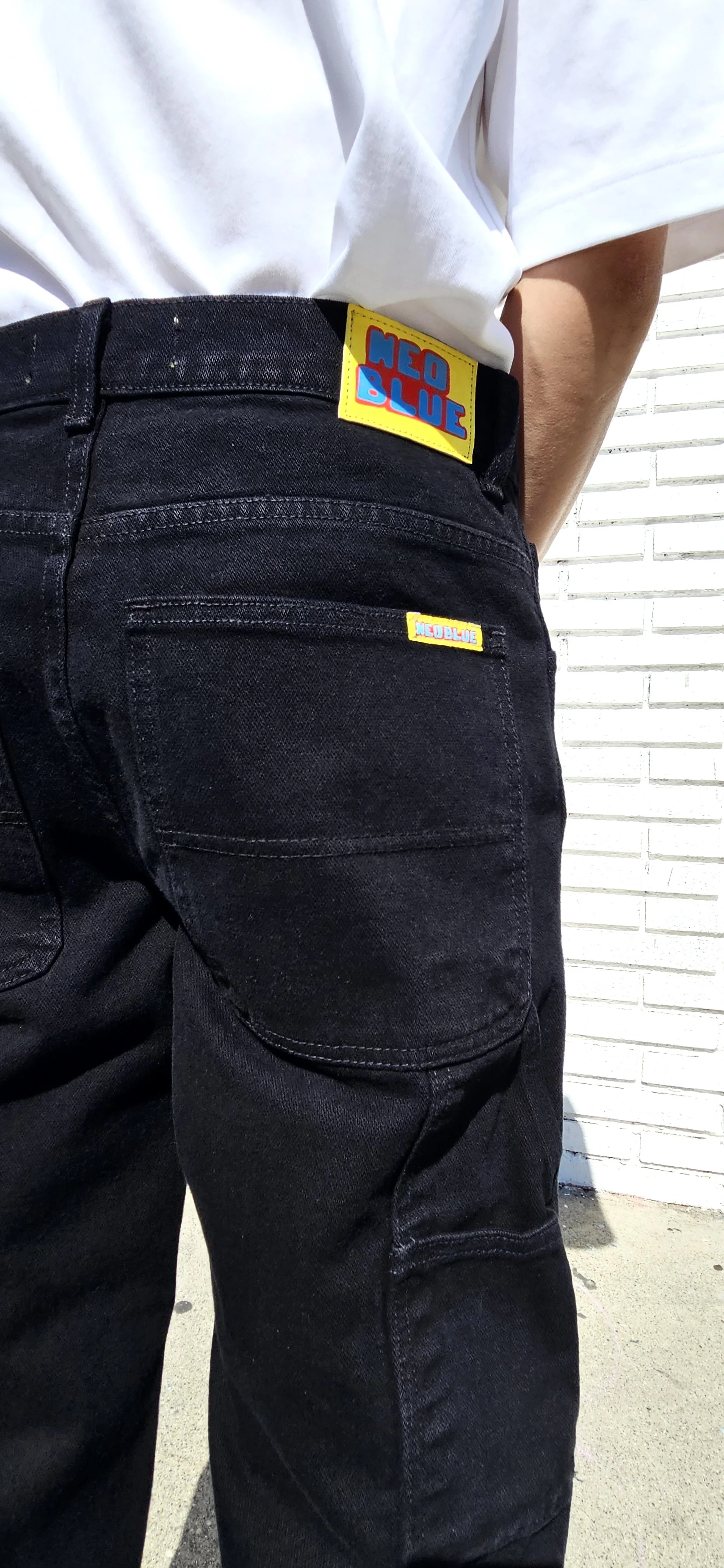 Back detail view of model in black baggy denim carpenter jeans.
