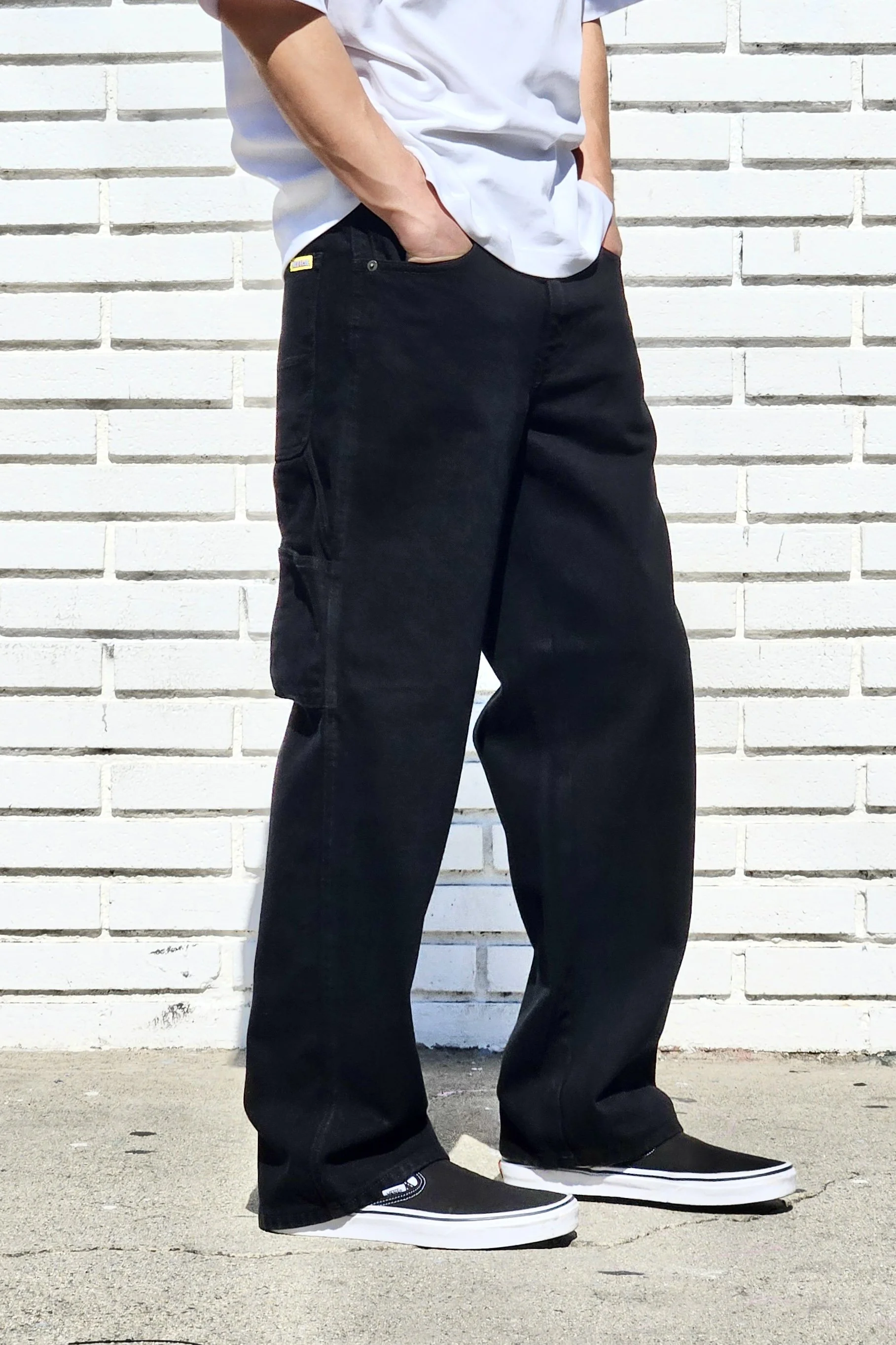 Side view of model in black baggy denim carpenter jeans.