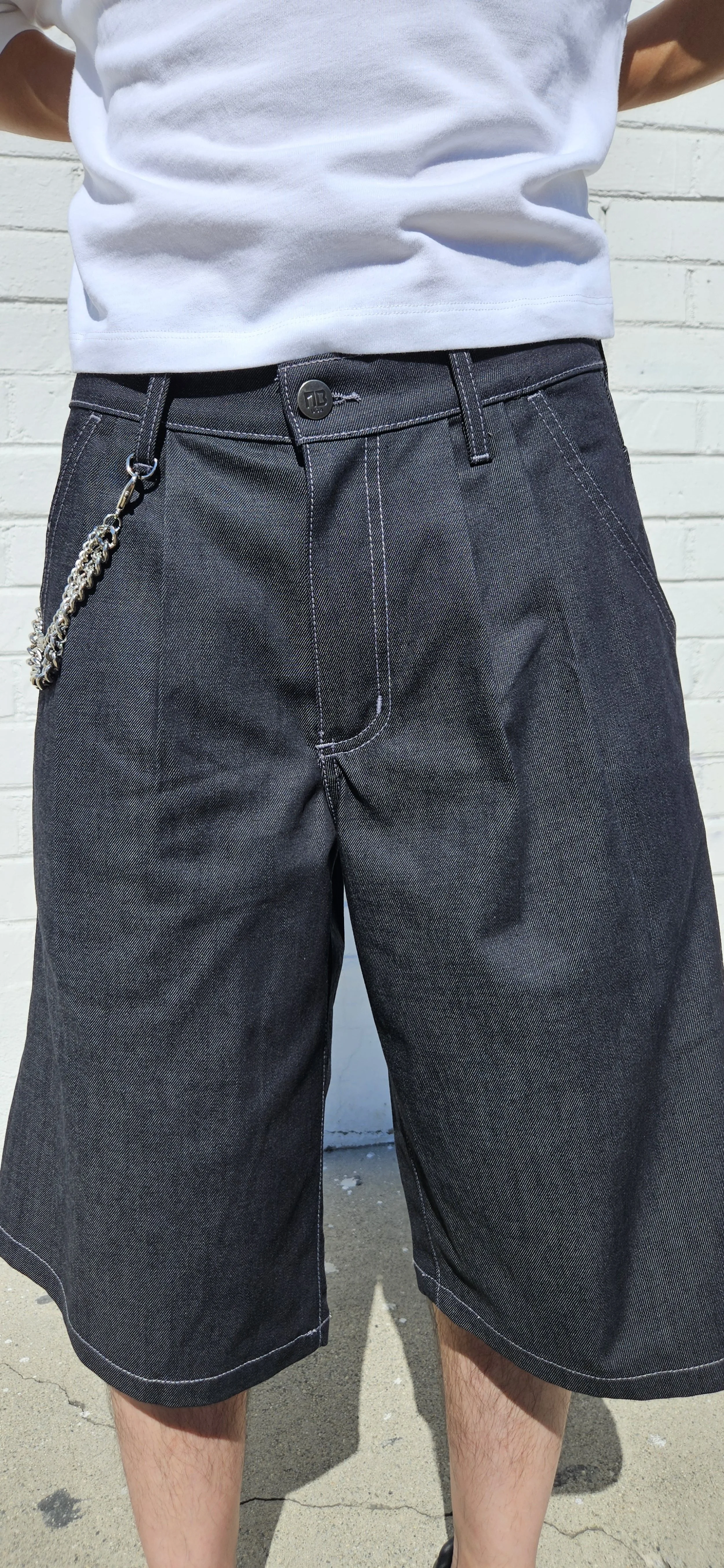 Front close up view of denim charcoal double pleated baggy jean short with d-ring attachment
