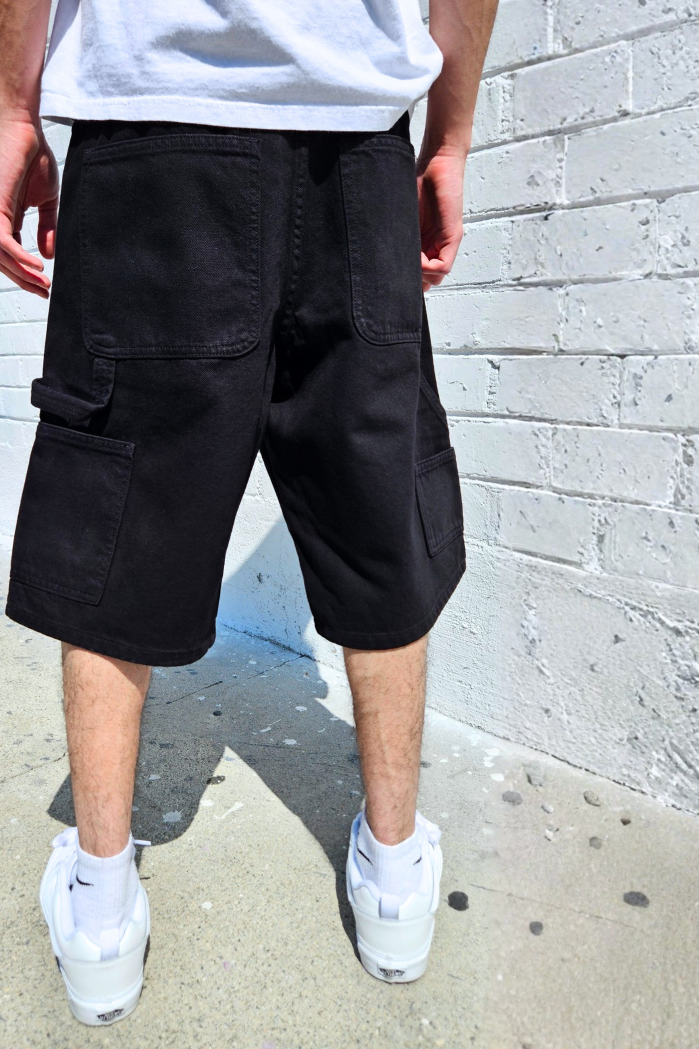 Relaxed fit denim carpenter shorts styled for casual streetwear outfits.