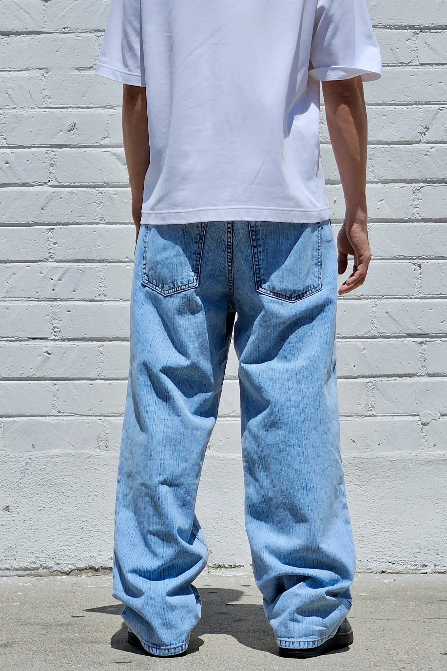 Back view of vertical pastel blue baggy jeans in slub denim.