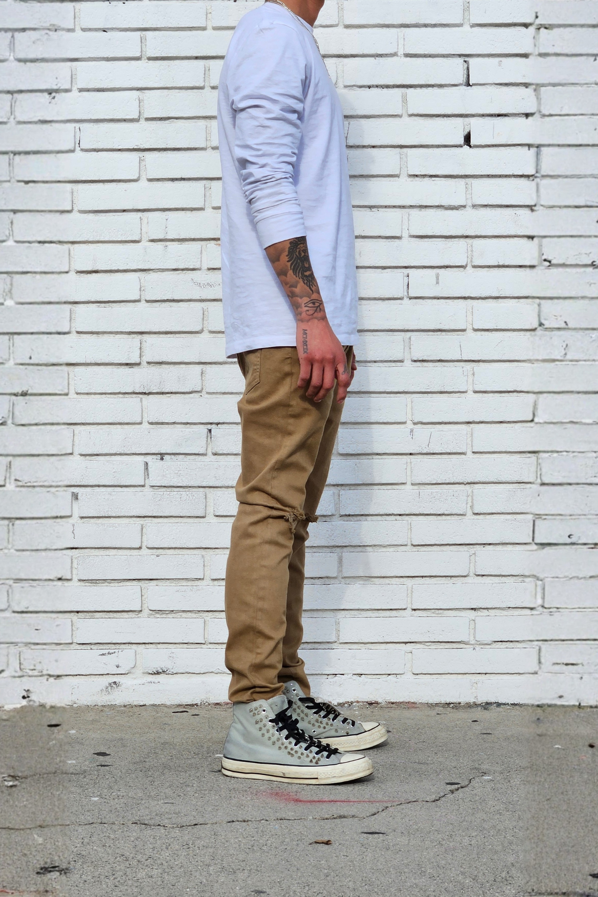 Side view of model in men's knee ripped camel super skinny jeans streetstyle outfit.